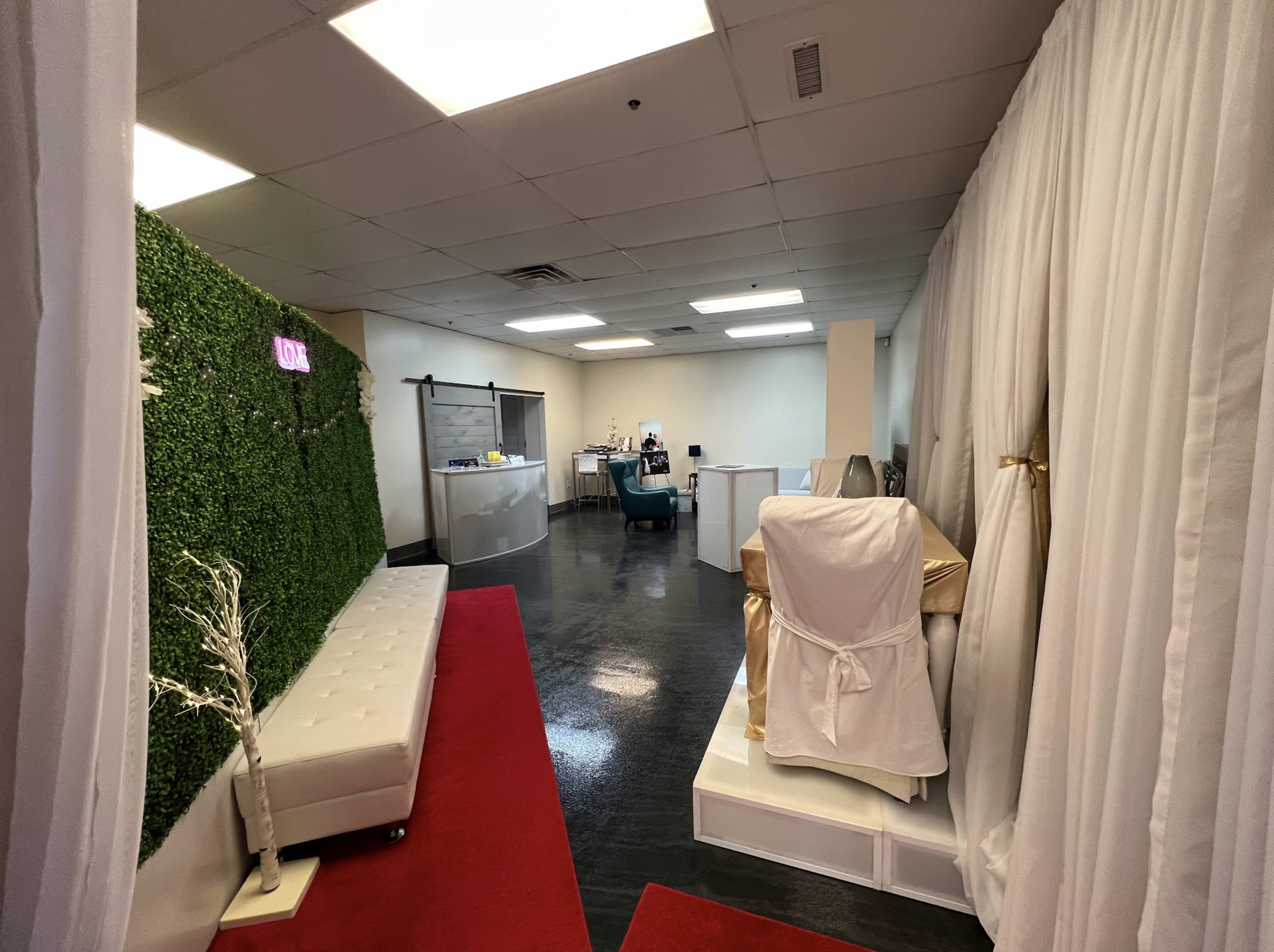 The image shows a spacious interior hallway leading to a reception area, with a green wall on one side and white drapes outlining a treatment room.