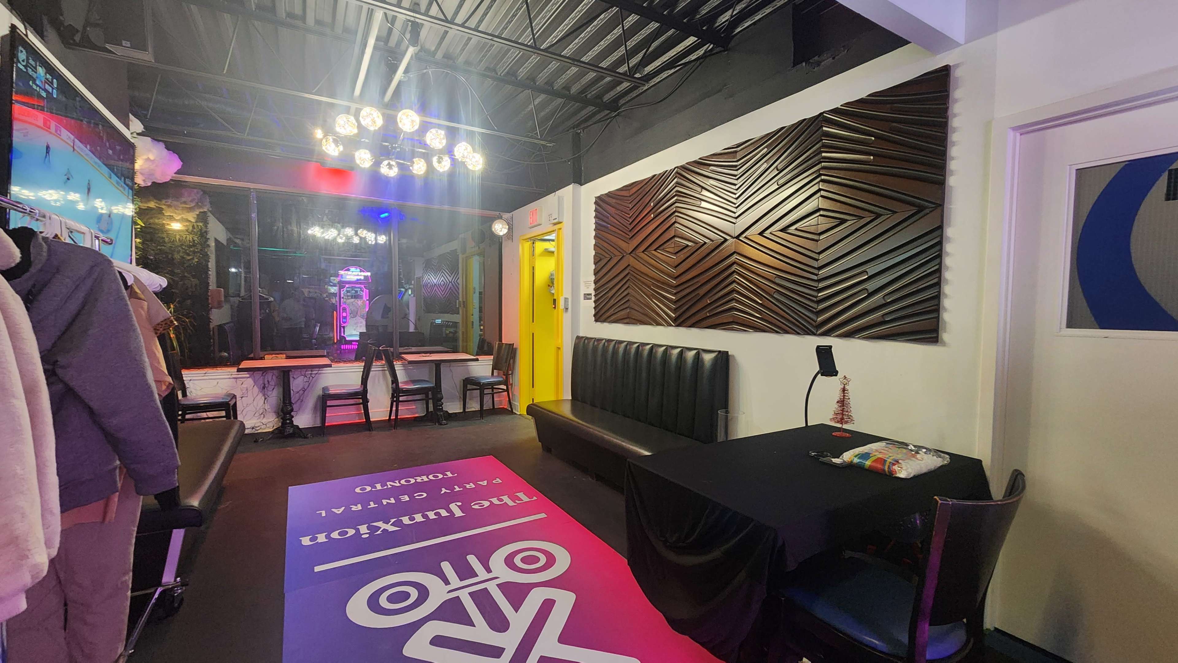The interior of a restaurant features a dark seating area, a vibrant yellow door, and a decorative wall with a geometric design.