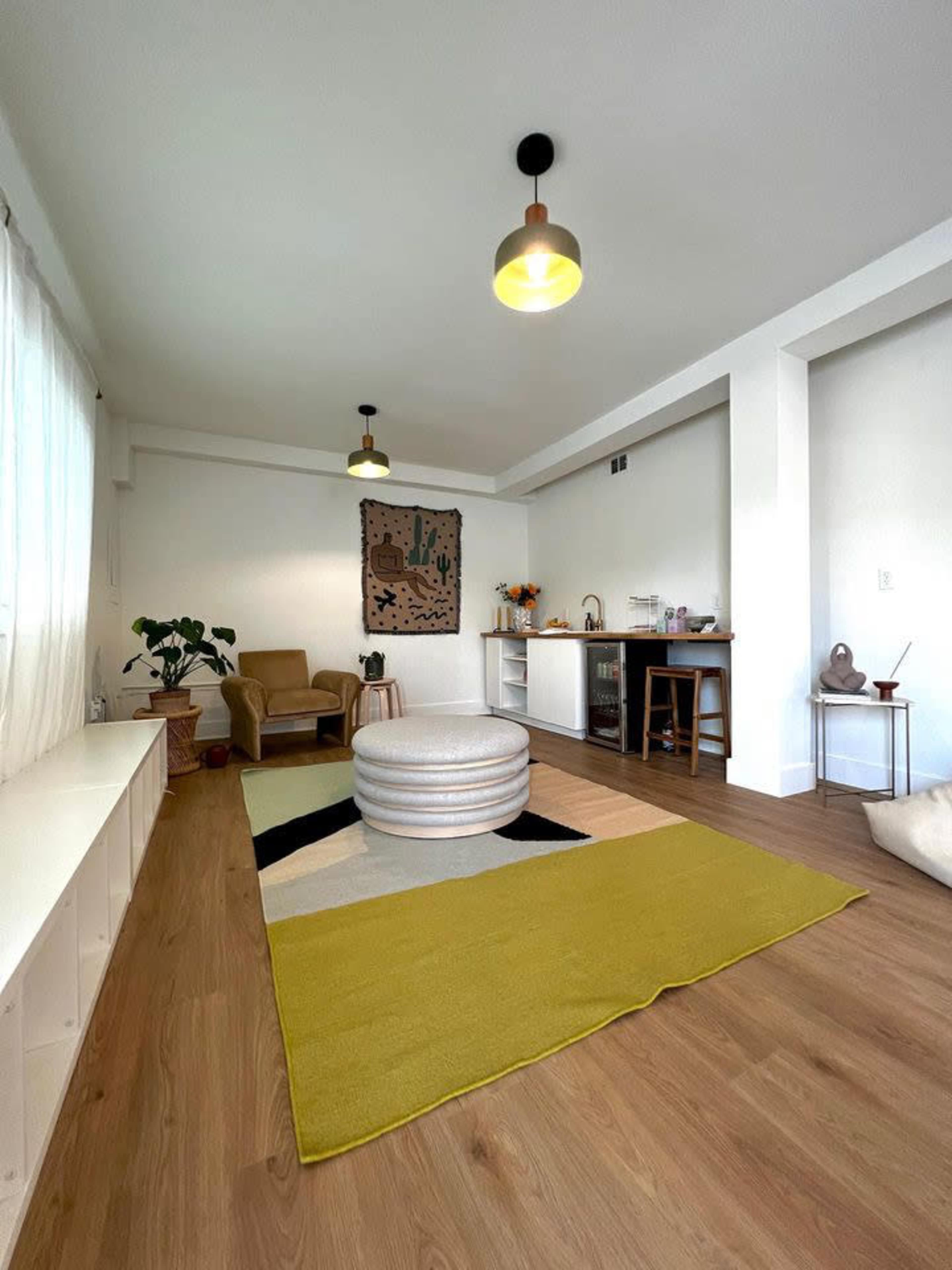 A spacious room with a patterned rug, a coffee table, an armchair, and a side counter with decorative items.