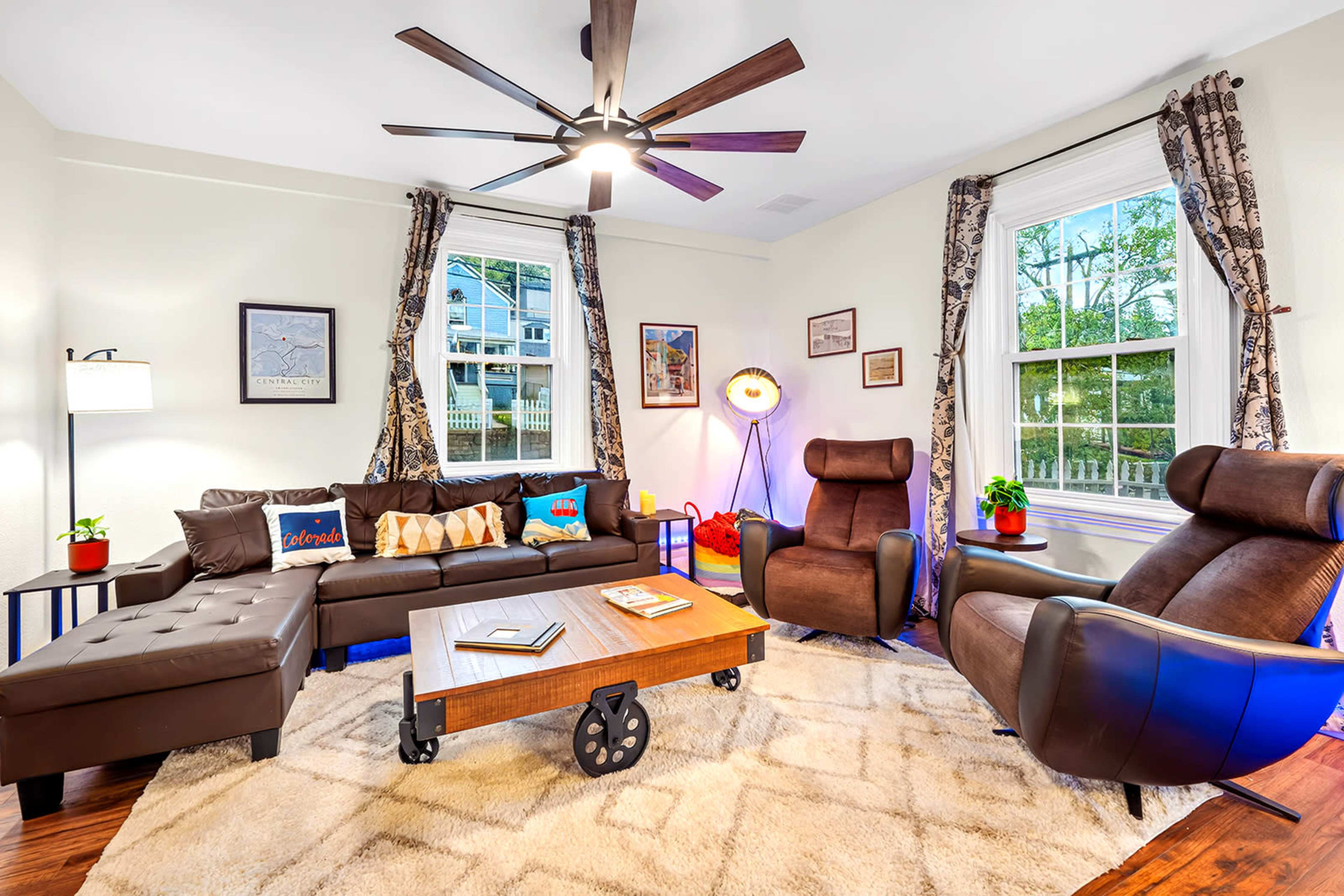 The image shows a well-furnished living room featuring a sectional sofa, two armchairs, a wooden coffee table, and decorative wall art.