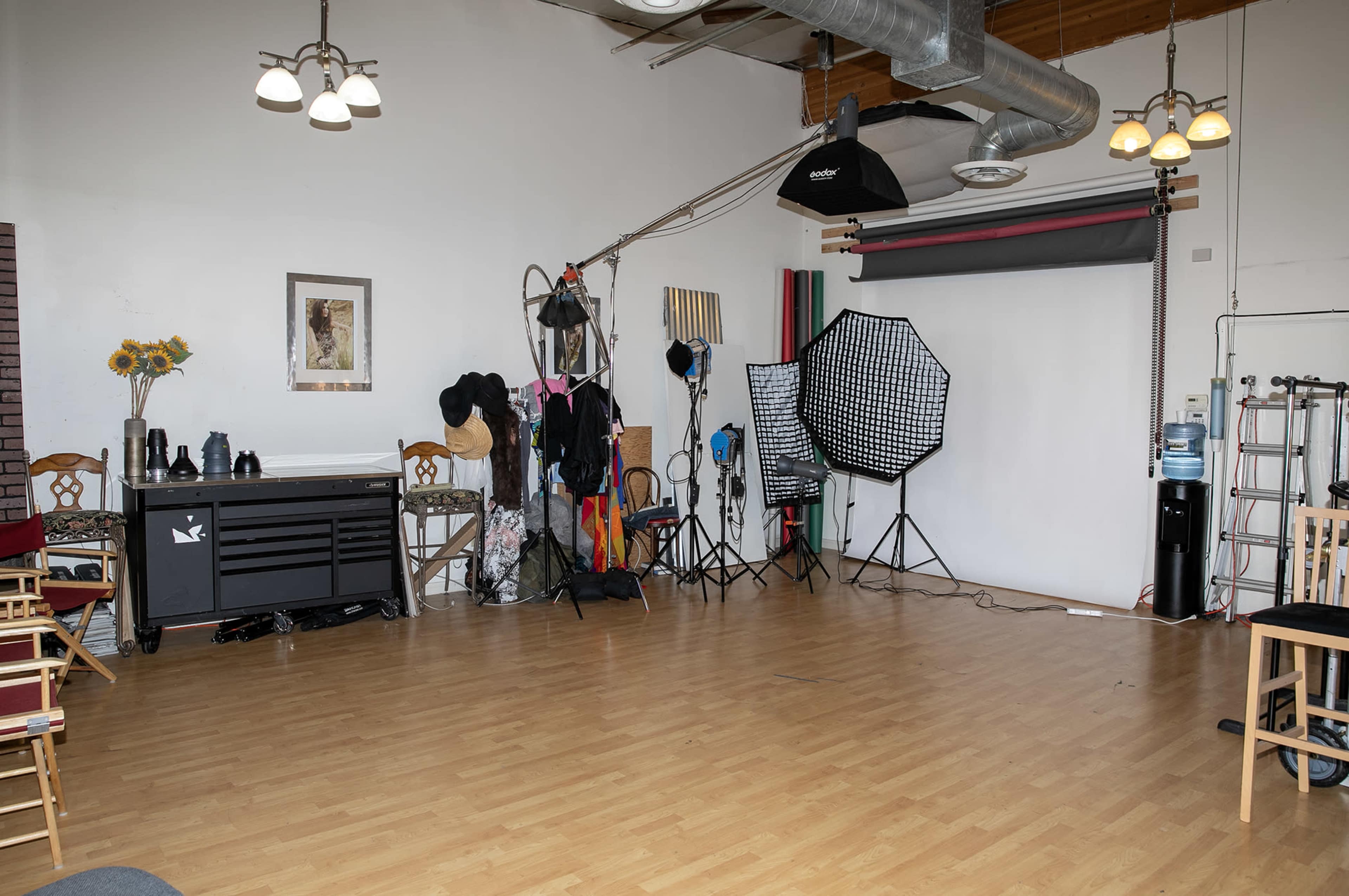 A photography studio with props, lighting equipment, and a backdrop set up against a wooden floor.
