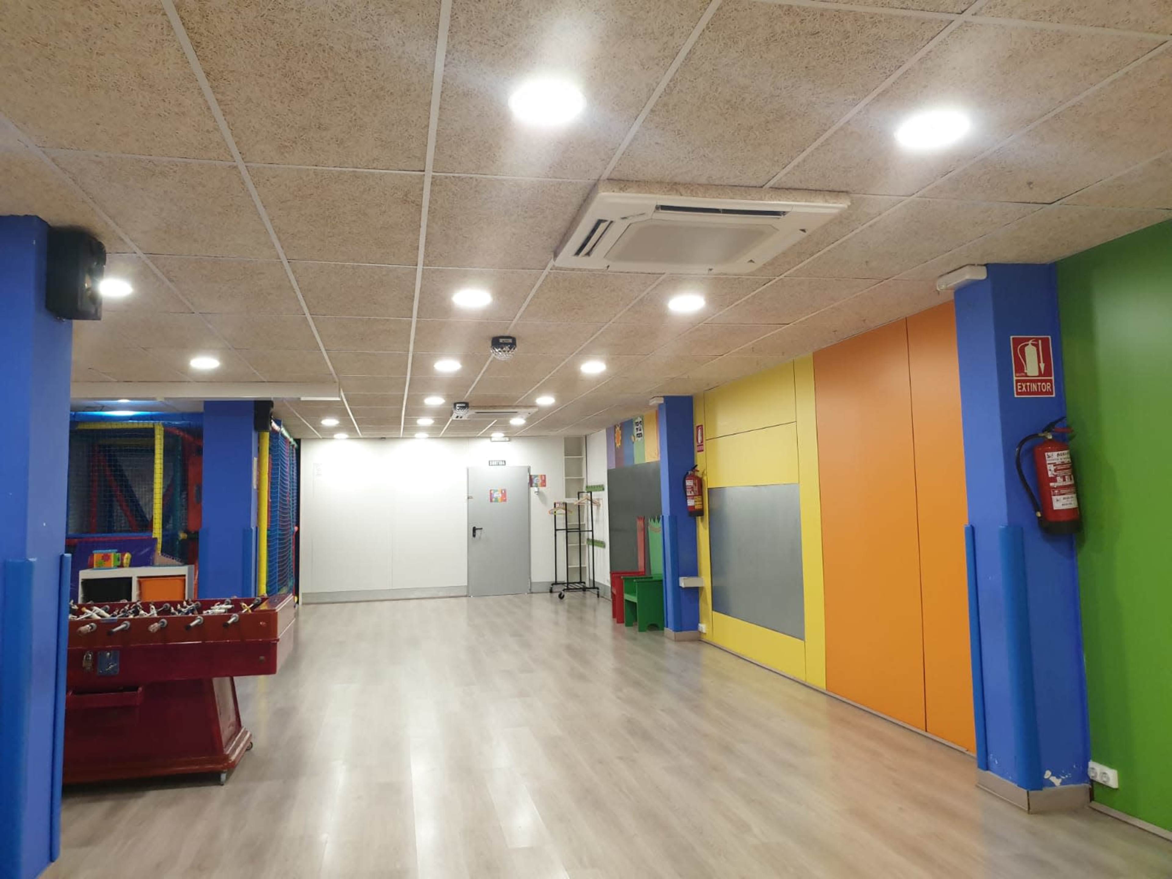 A brightly colored indoor playroom with games, colorful walls, and a wooden foosball table.