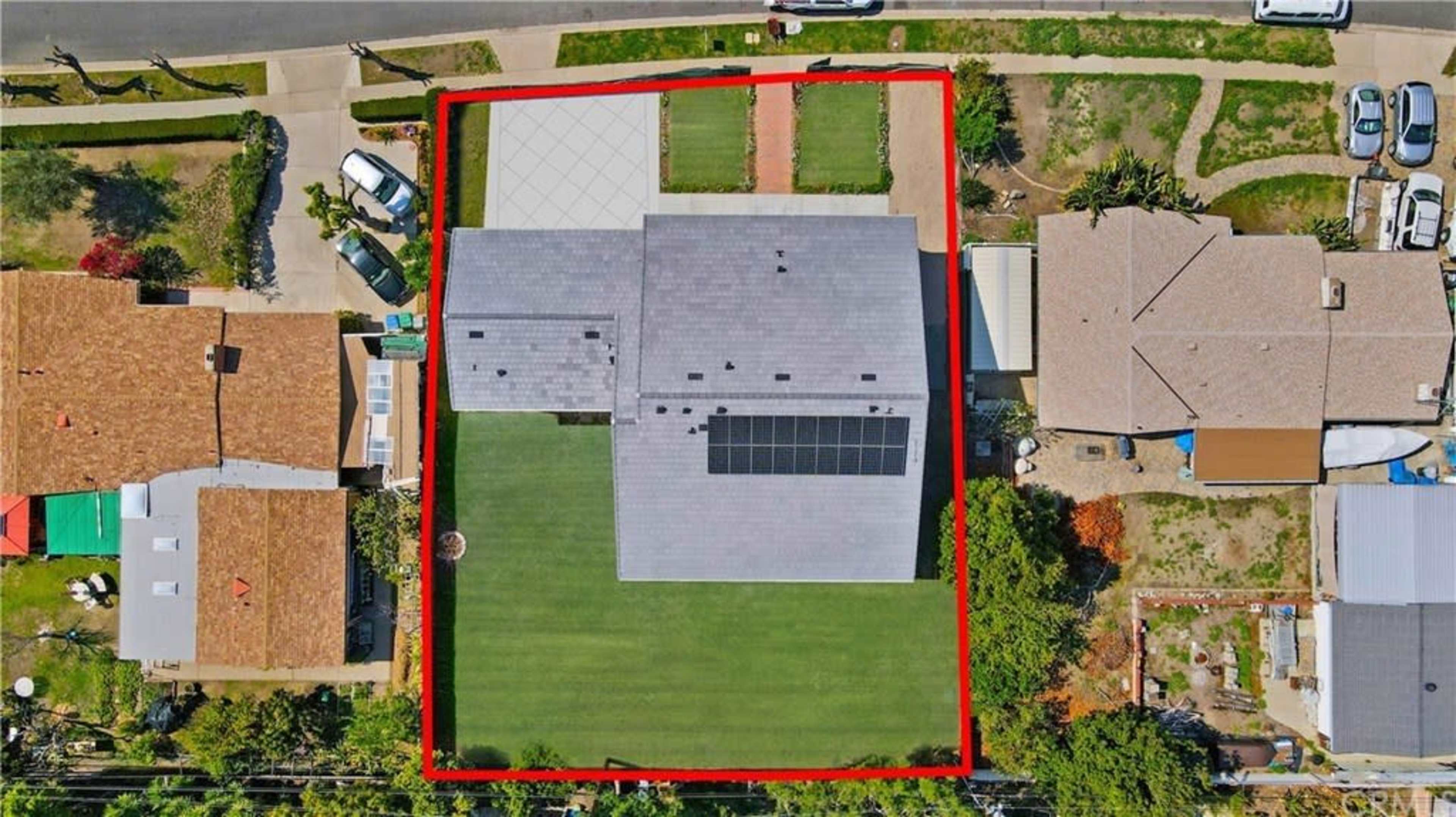 The image shows an aerial view of a house with a solar panel roof, surrounded by a red boundary, with adjacent homes and a paved driveway.