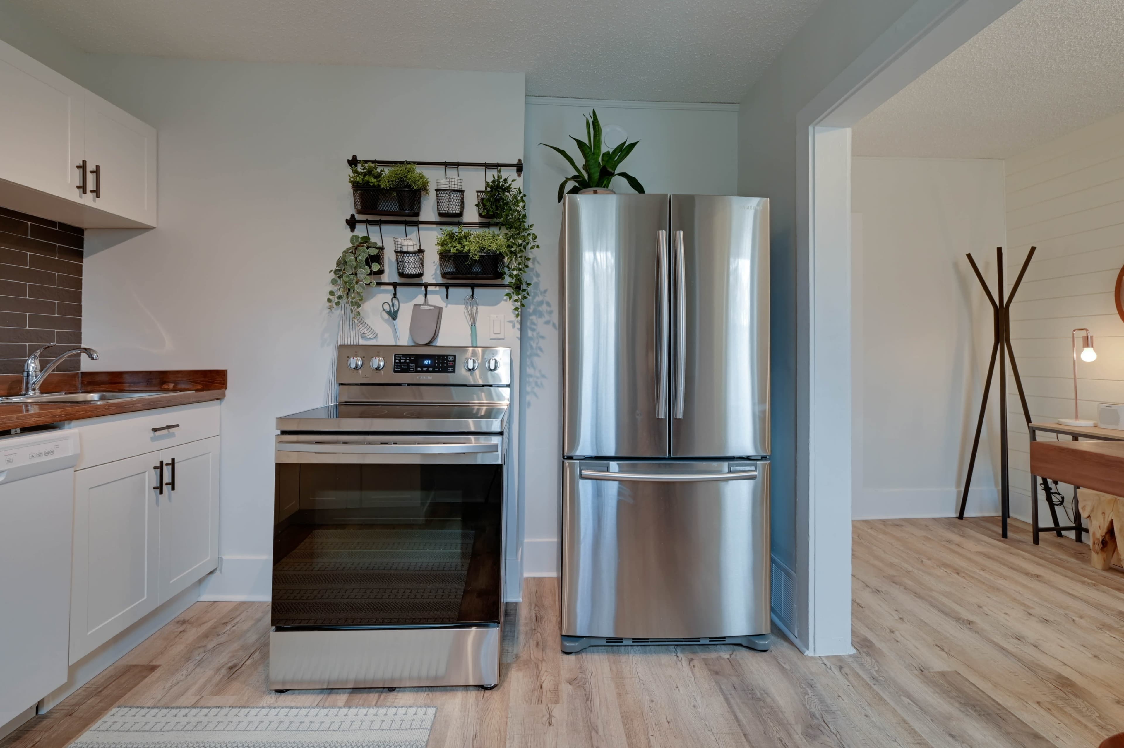 A modern kitchen featuring a stainless steel refrigerator and an oven next to a wall-mounted plant shelf.