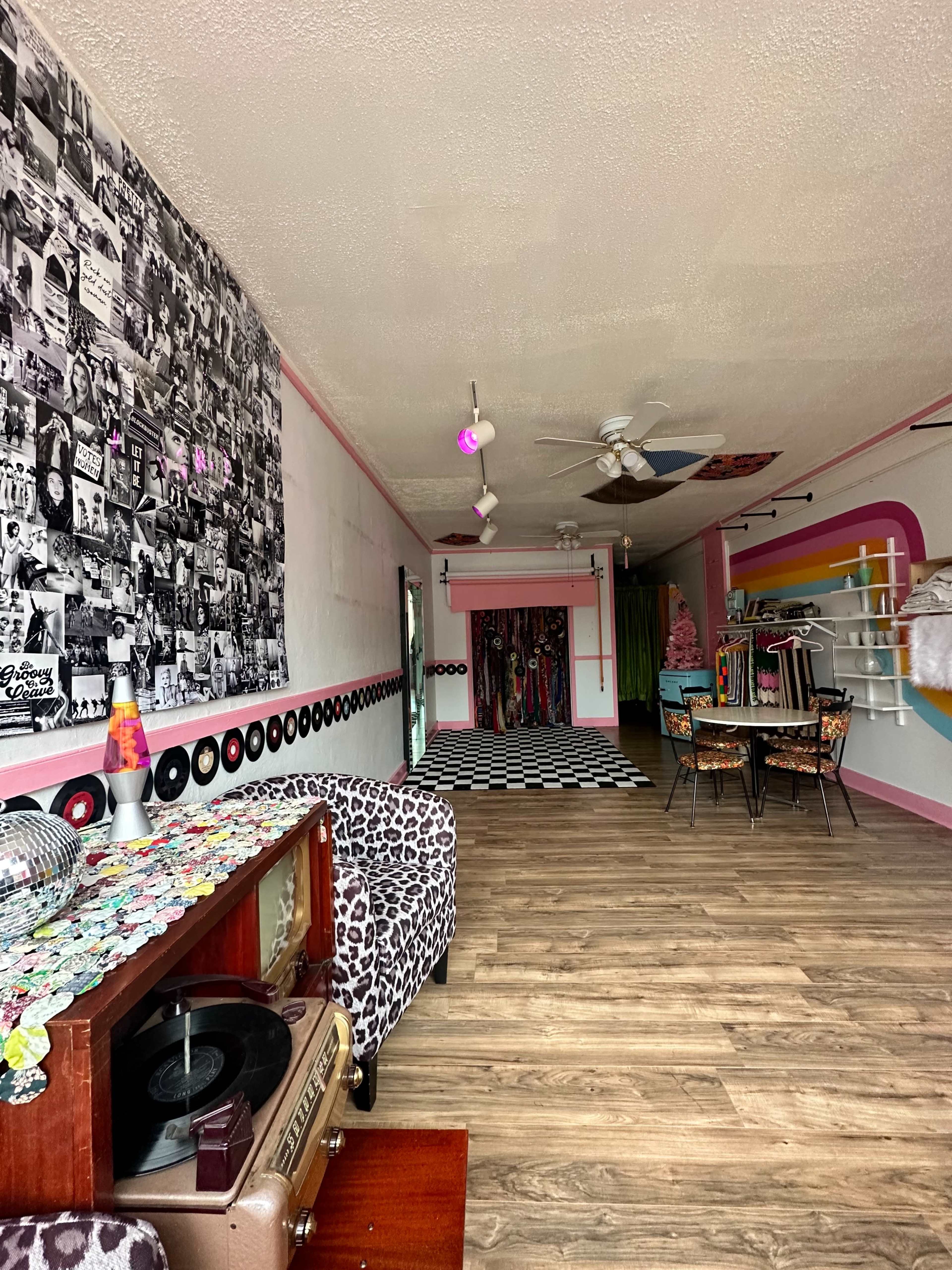 A boutique interior featuring a black-and-white photo wall, colorful decor, a patterned floor, and a retro record player.