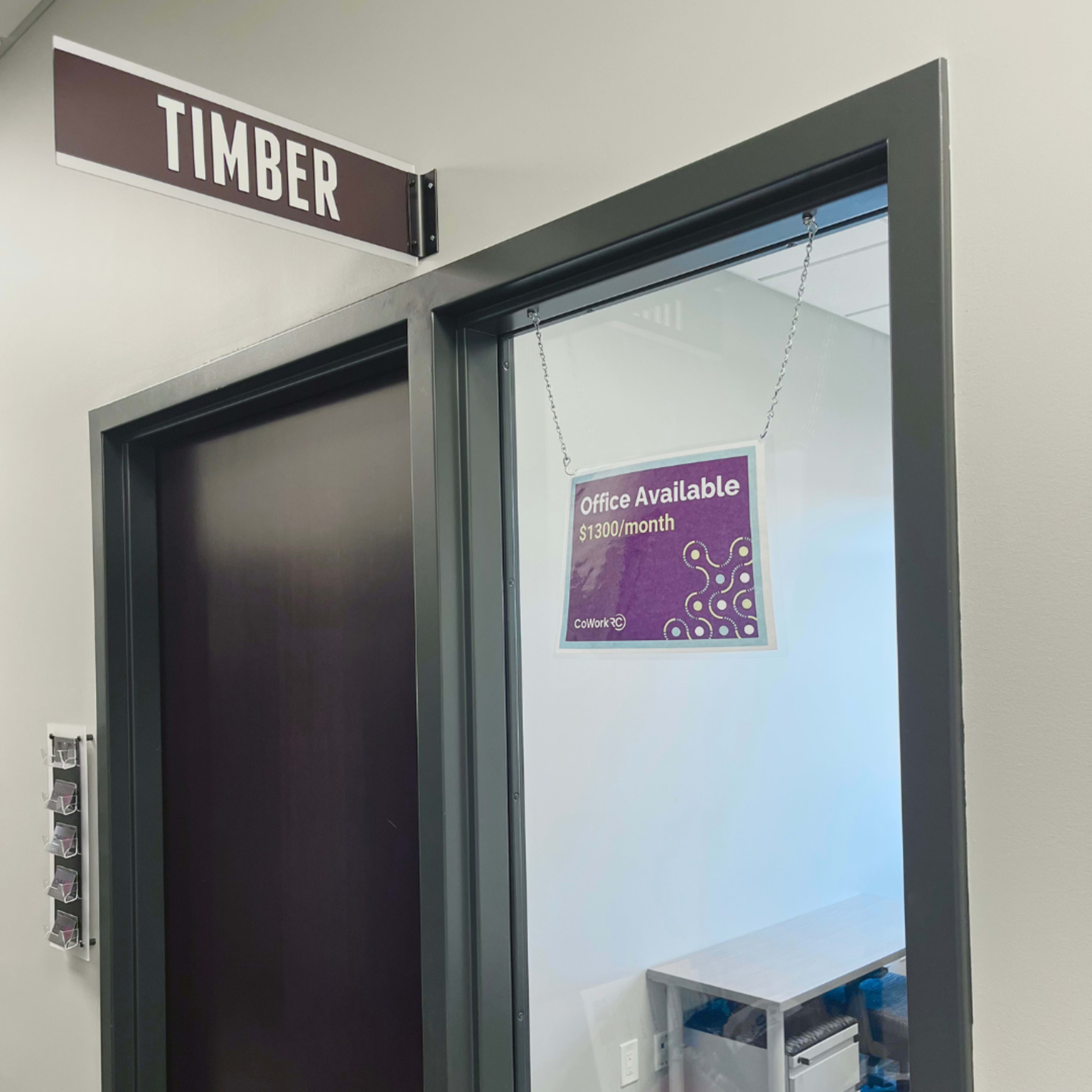 The image shows a door with a sign reading "Timber" above it and a hanging sign that states "Office Available $1300/month."