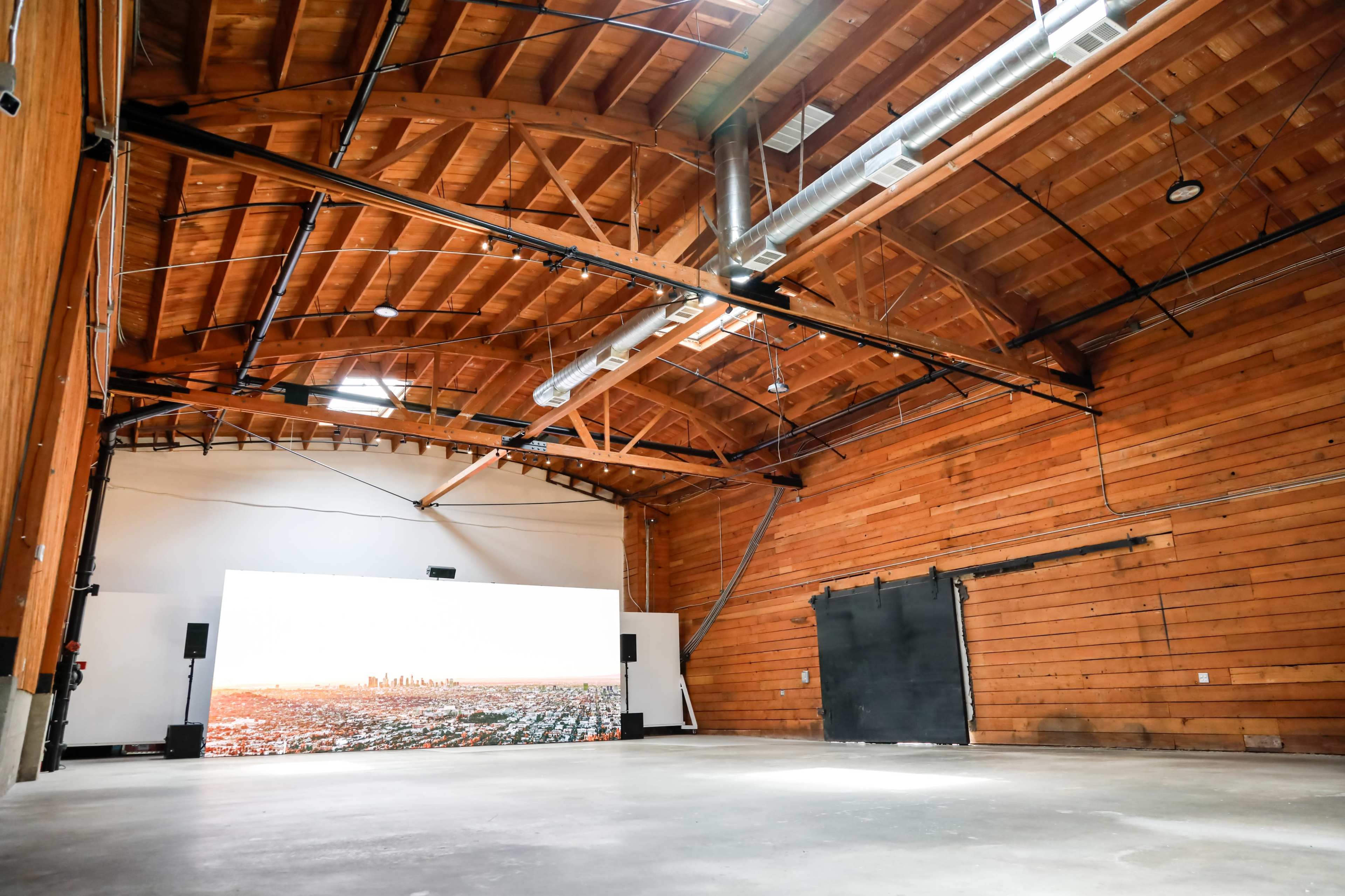 A spacious, empty wooden interior with a large screen displaying a cityscape at one end.