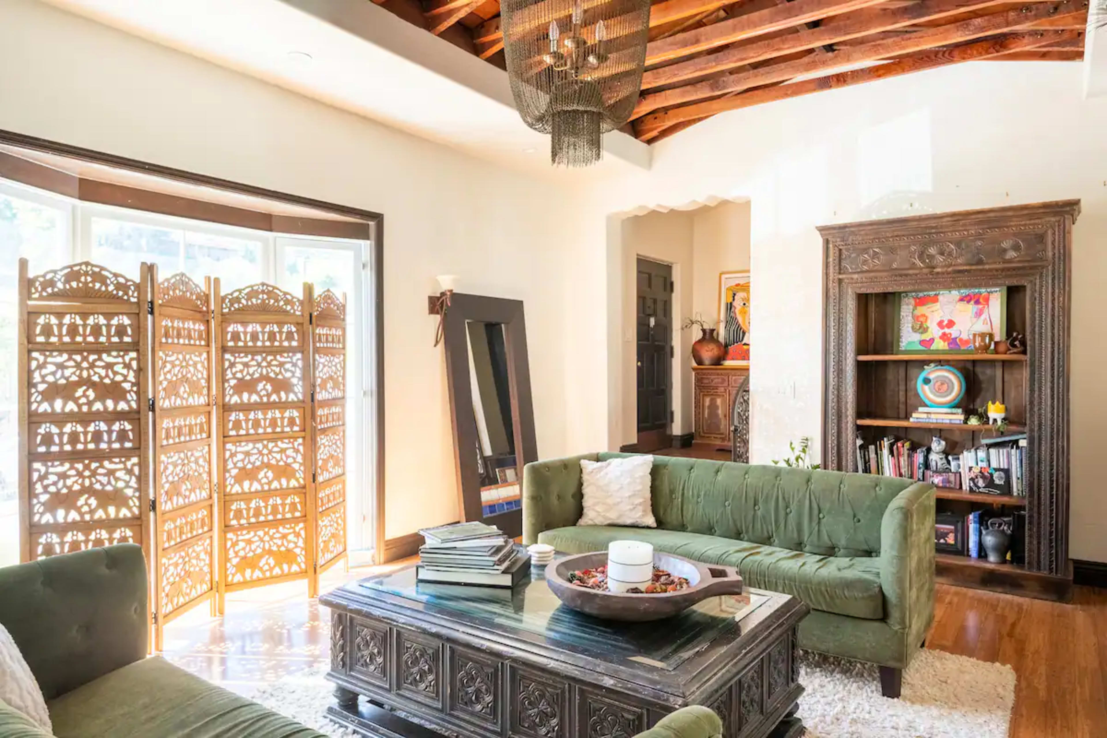 The living room features a green sofa set, a wooden coffee table, a decorative folding screen, and bookshelves against the walls.