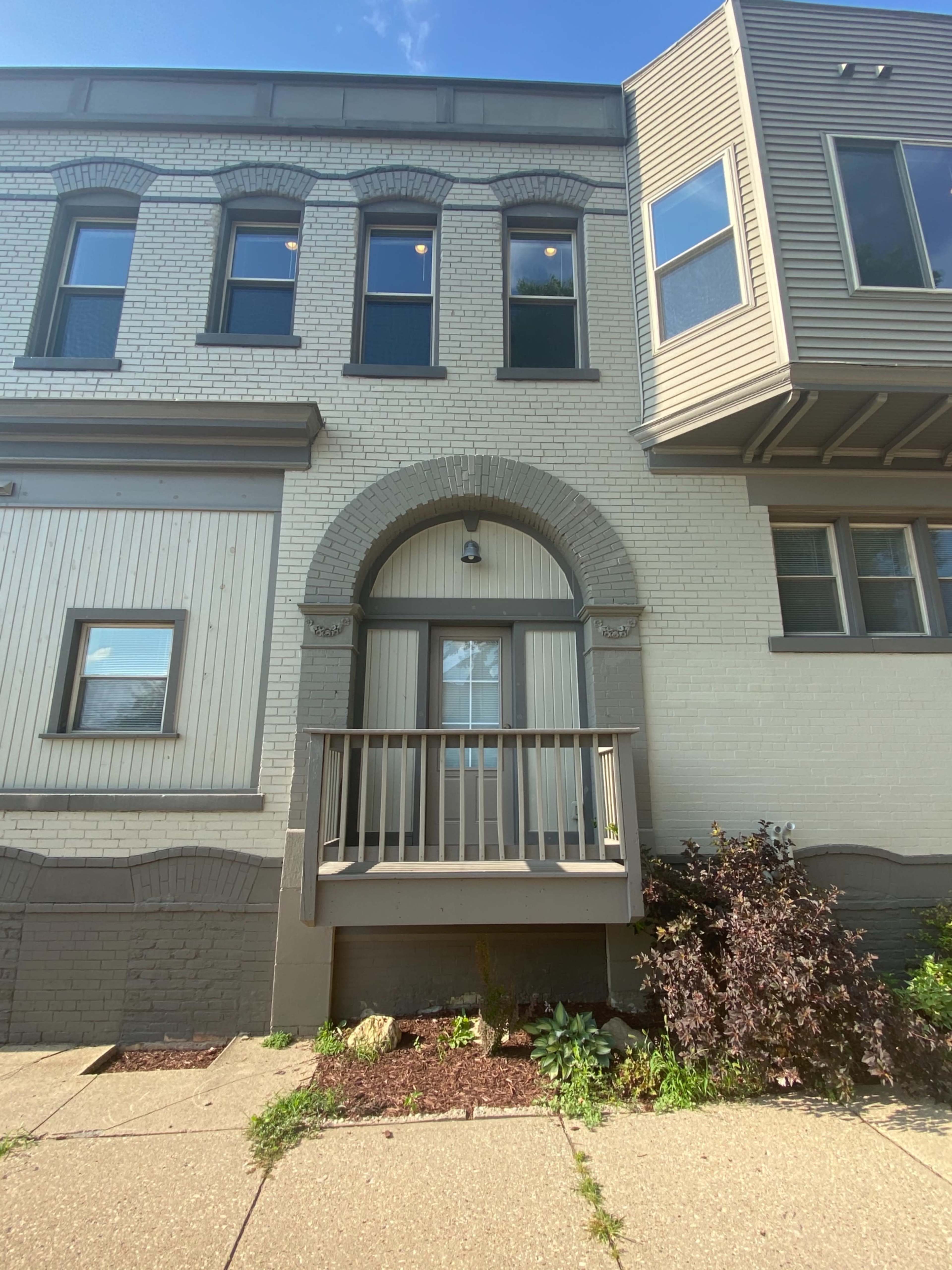 A two-story brick building with a decorative arch over the entrance and a small balcony.