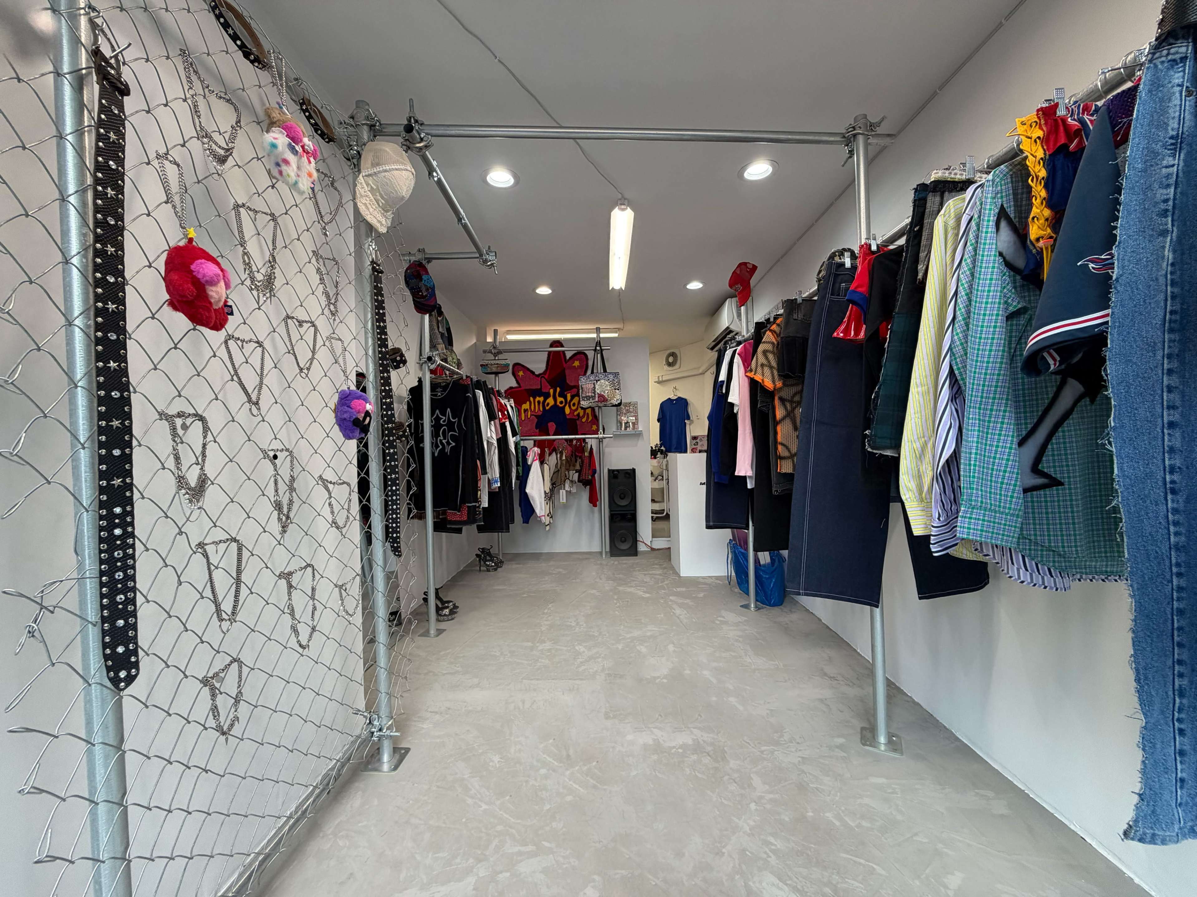 A clothing store is depicted with a grid of hanging garments on both sides and a gated partition in the center.