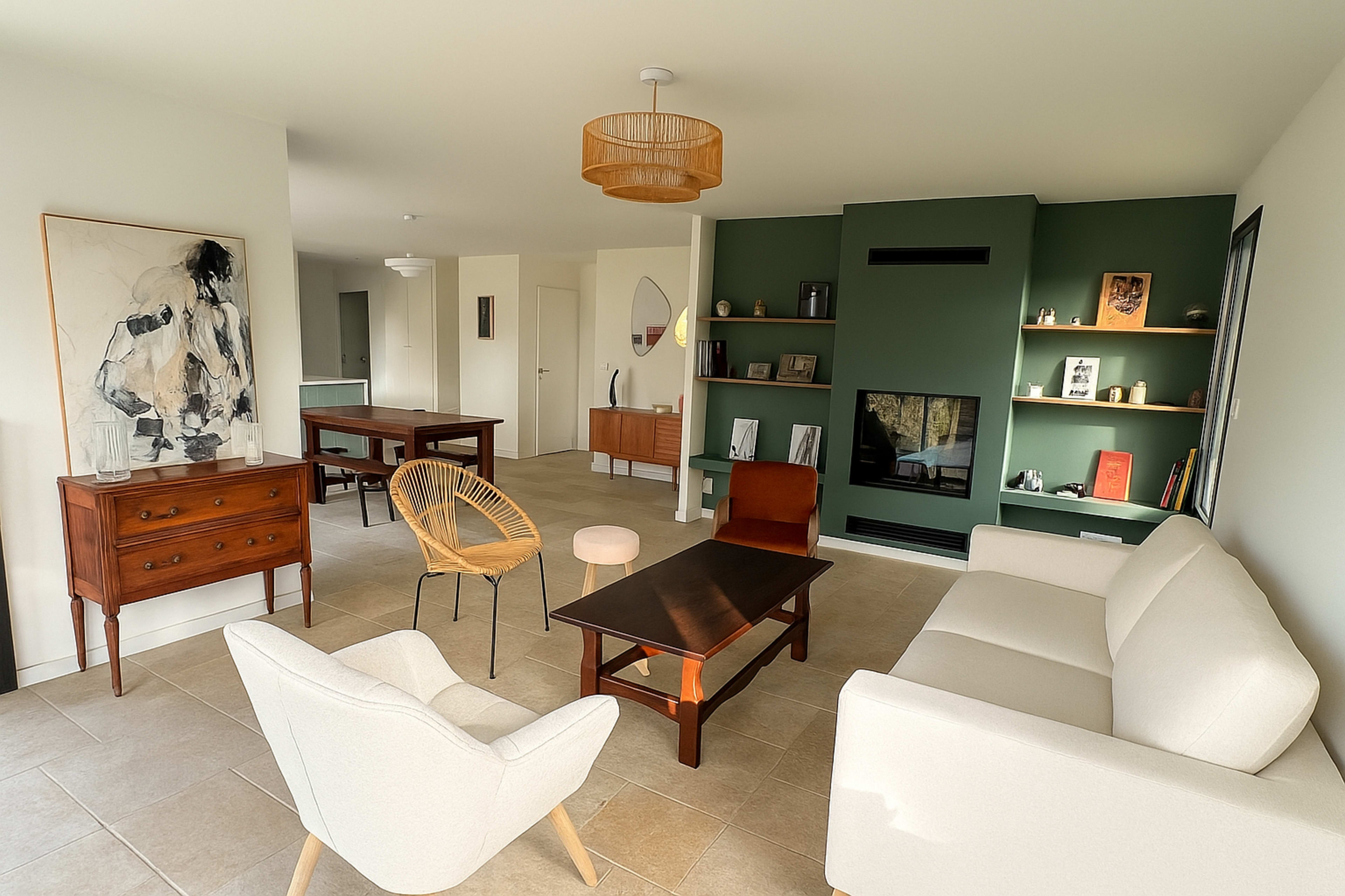 A modern living room features a mix of wooden furniture, a cozy seating area, and a green accent wall with shelves displaying decor items.