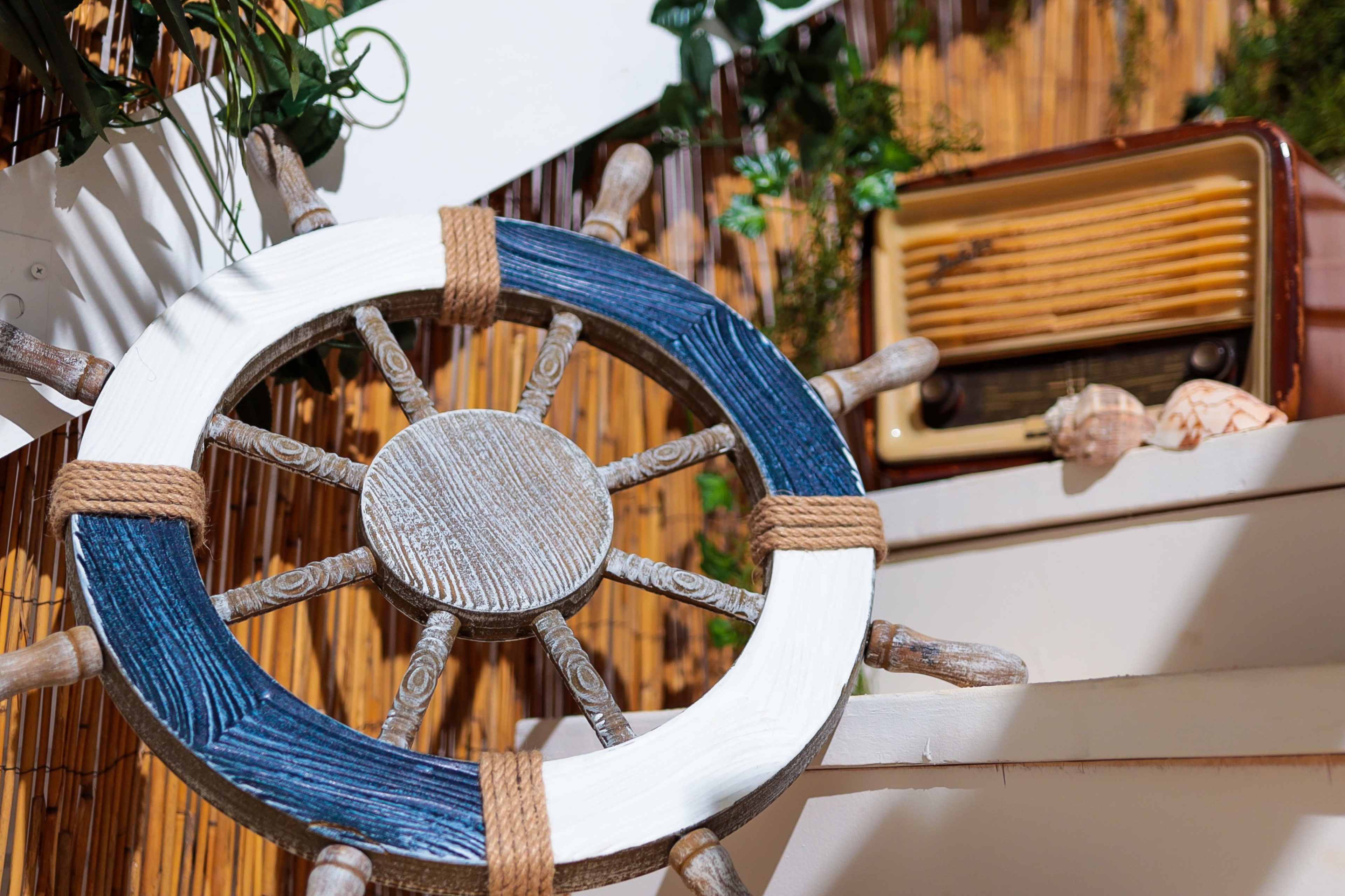 A nautical-themed scene features a decorative ship's wheel in the foreground and an old radio on a shelf in the background.