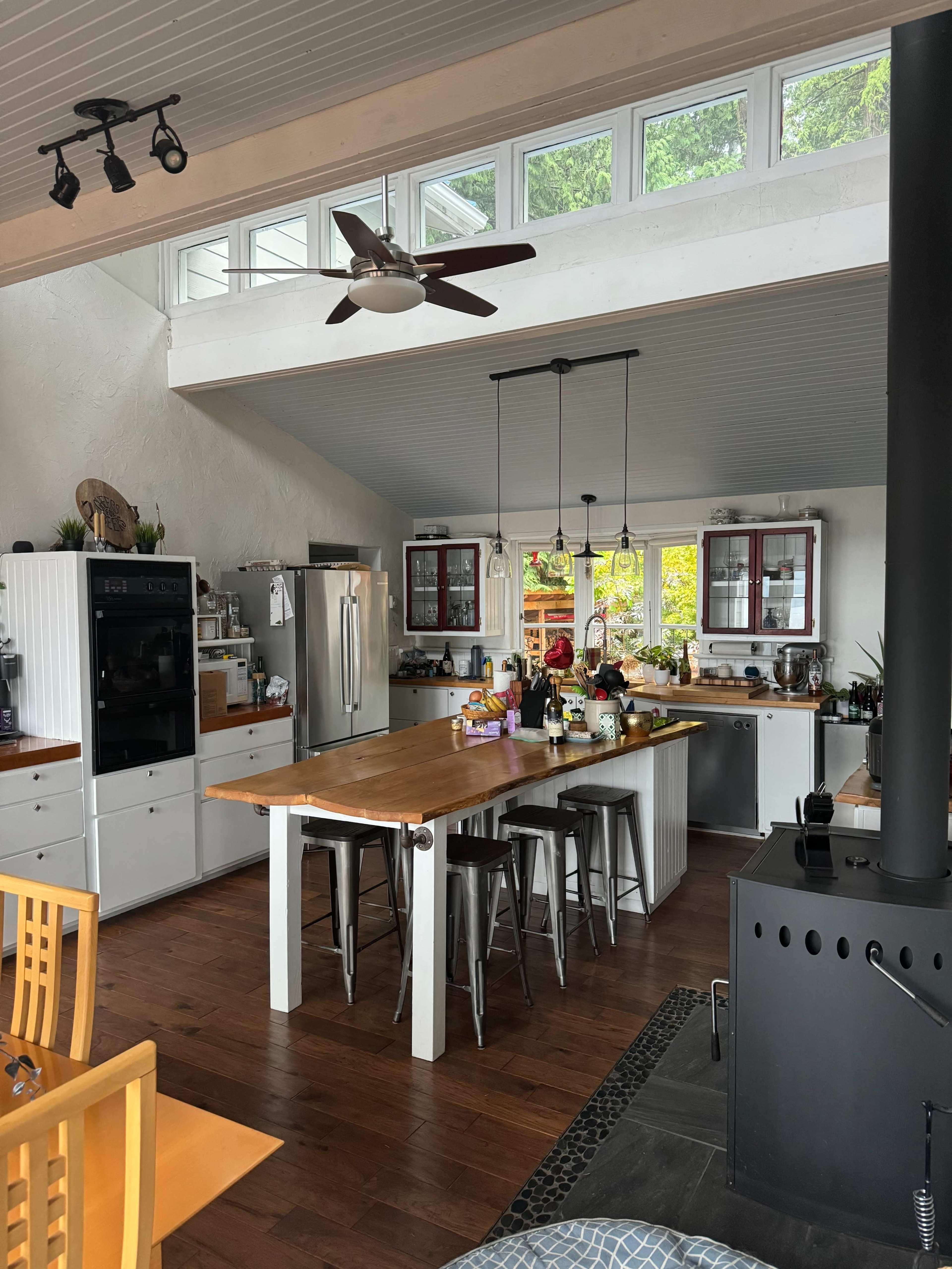 A spacious kitchen featuring a central island with bar stools, modern appliances, and large windows that provide natural light.
