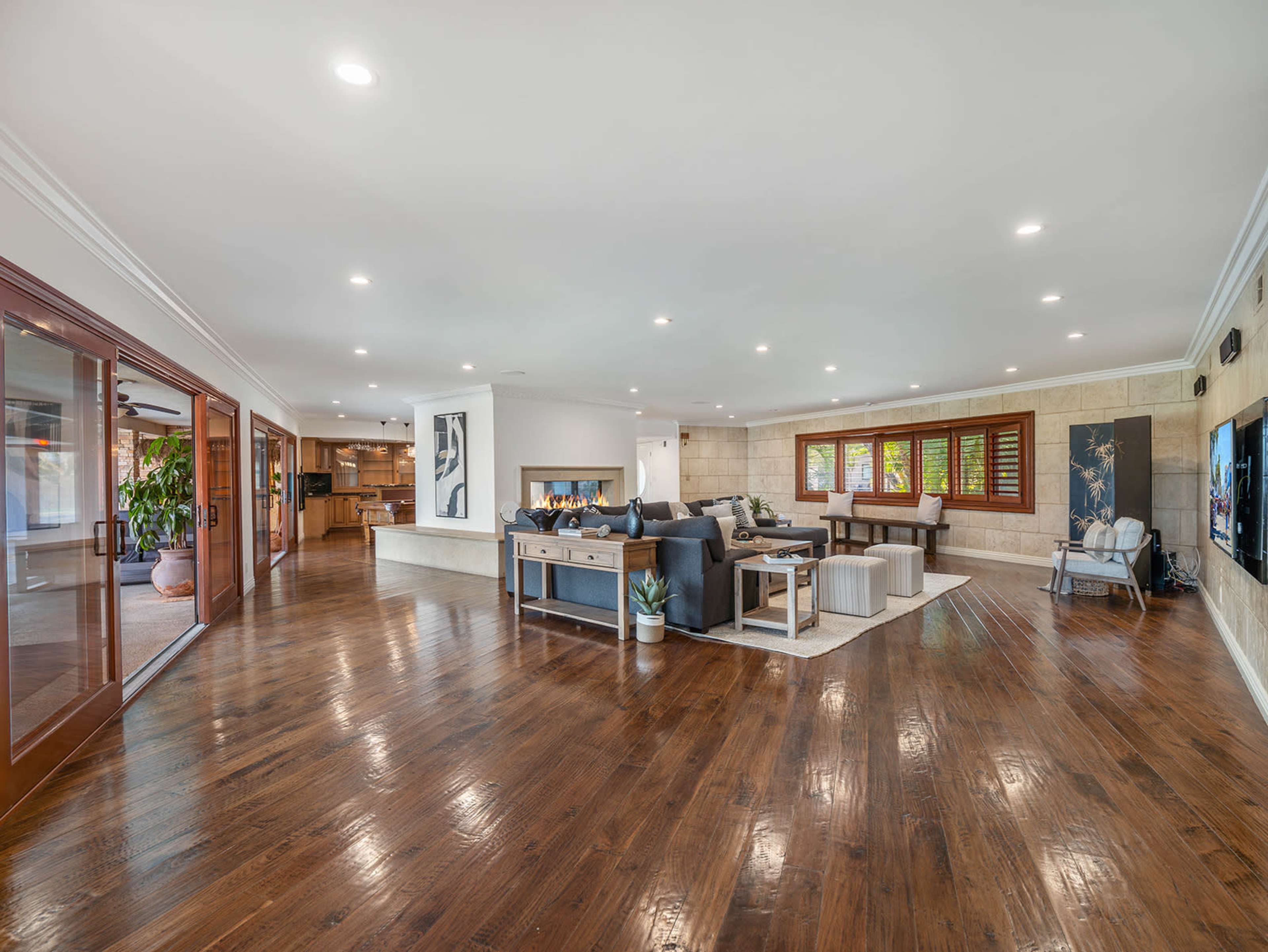 A spacious, open-concept living area with hardwood floors, modern furniture, and large windows allowing natural light.