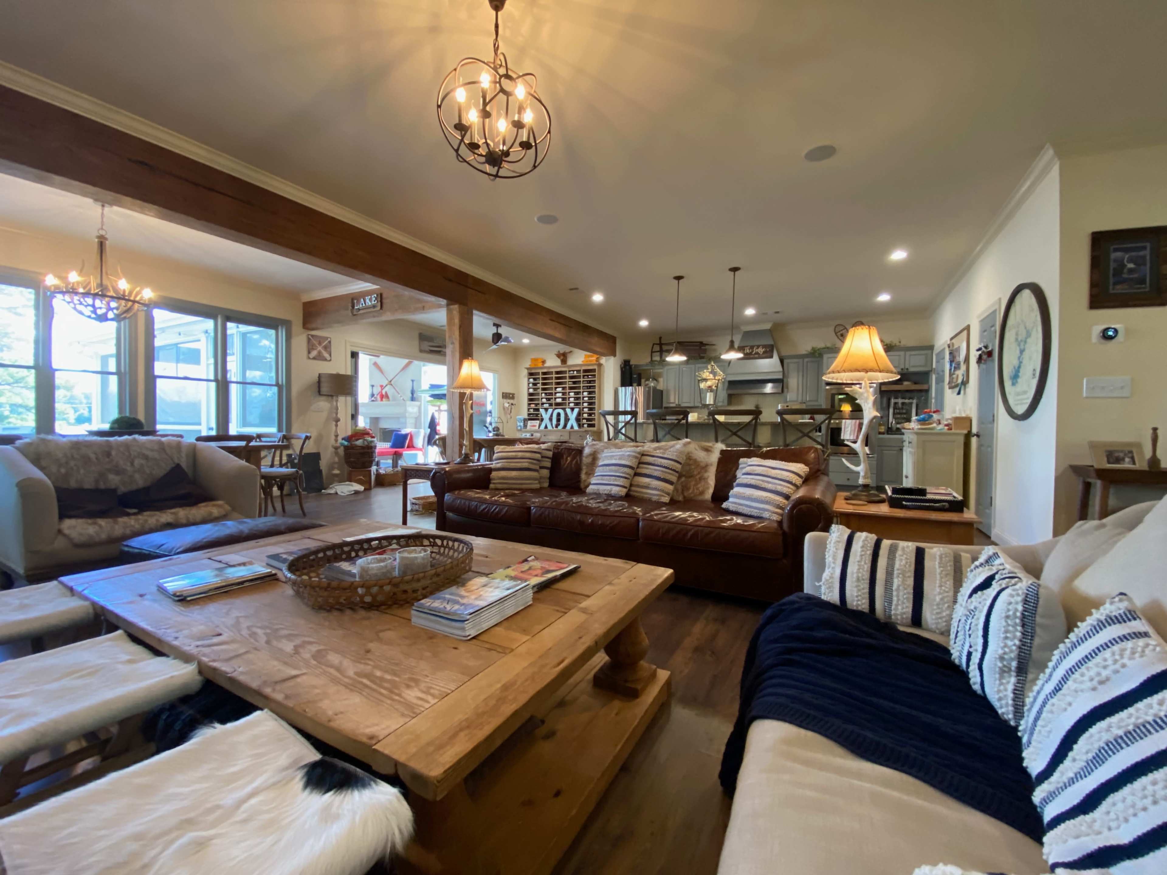 A spacious living room with a large leather sofa, wooden coffee table, and an open kitchen visible in the background.
