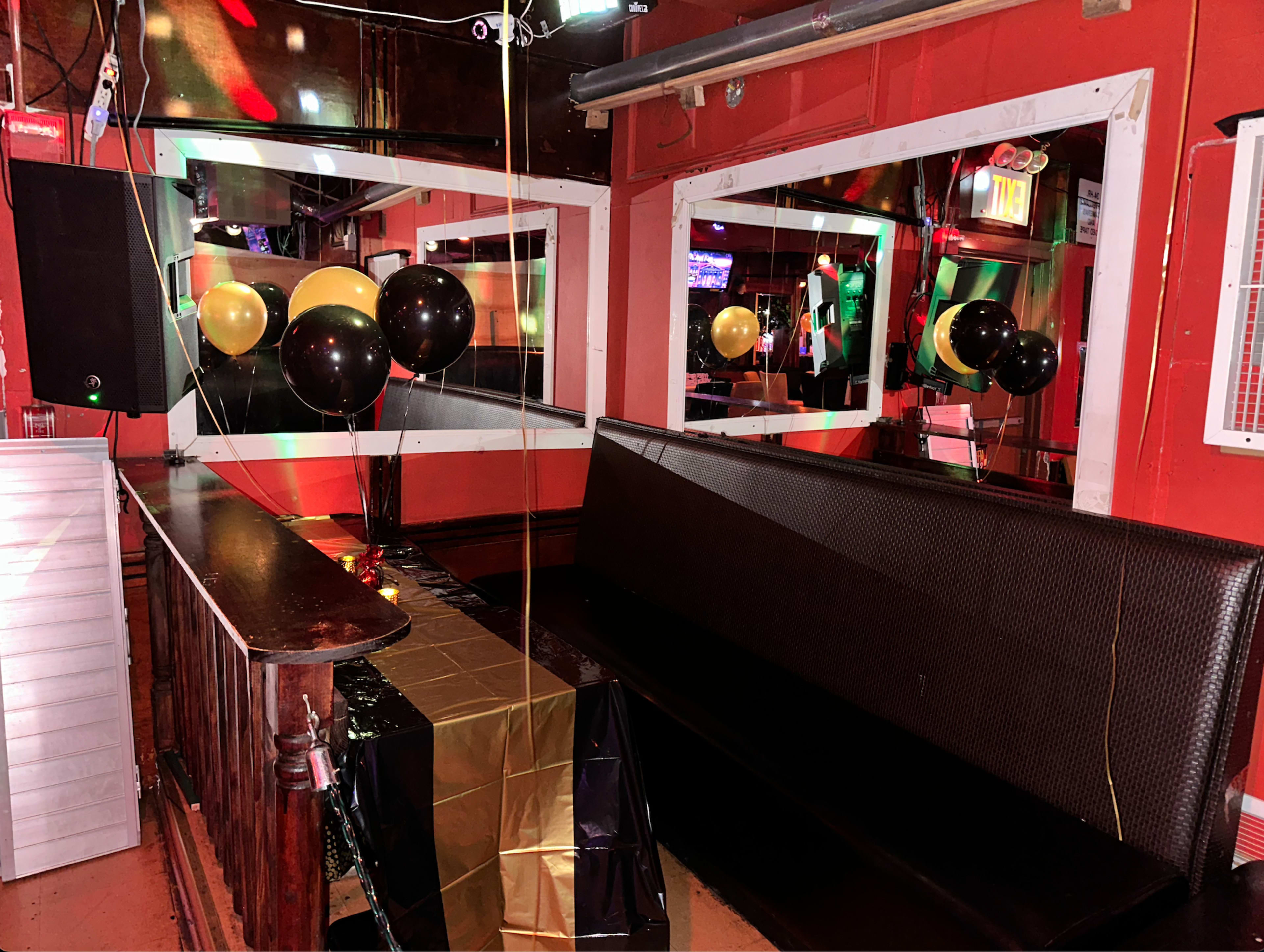 A small bar area with a black and gold themed decoration featuring balloons and mirrors on the walls.