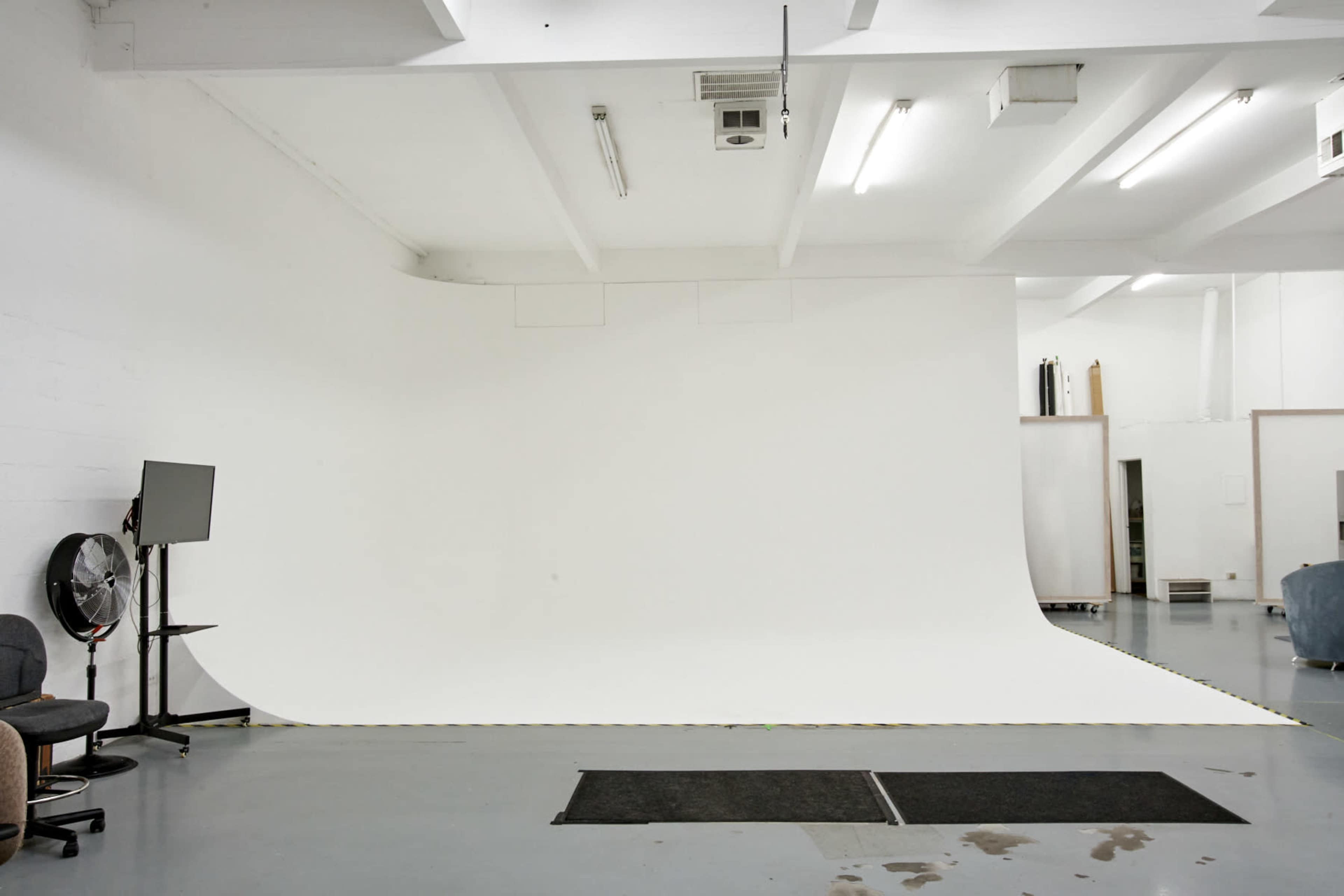 A spacious photography studio features a seamless white backdrop and minimalist furnishings.