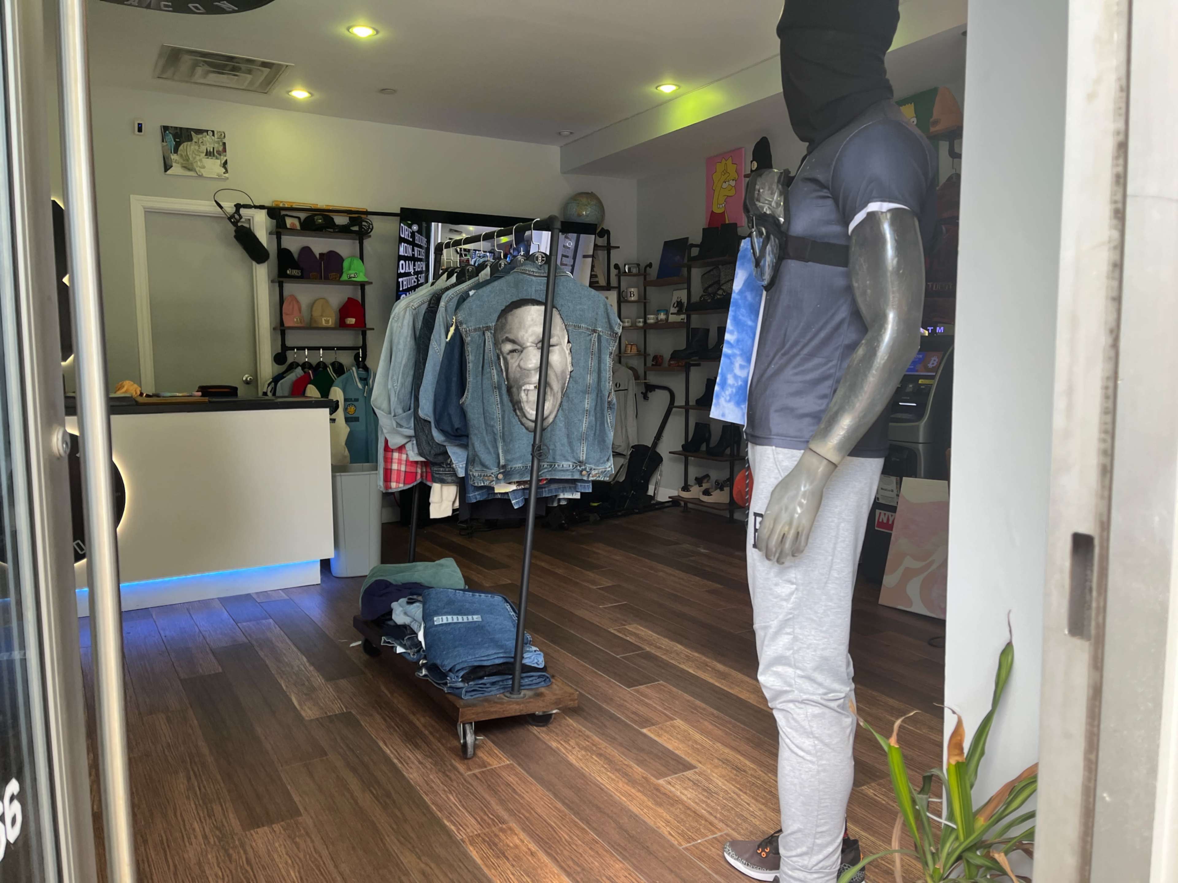 A store interior features a mannequin dressed in casual attire beside a rack displaying various hanging garments.