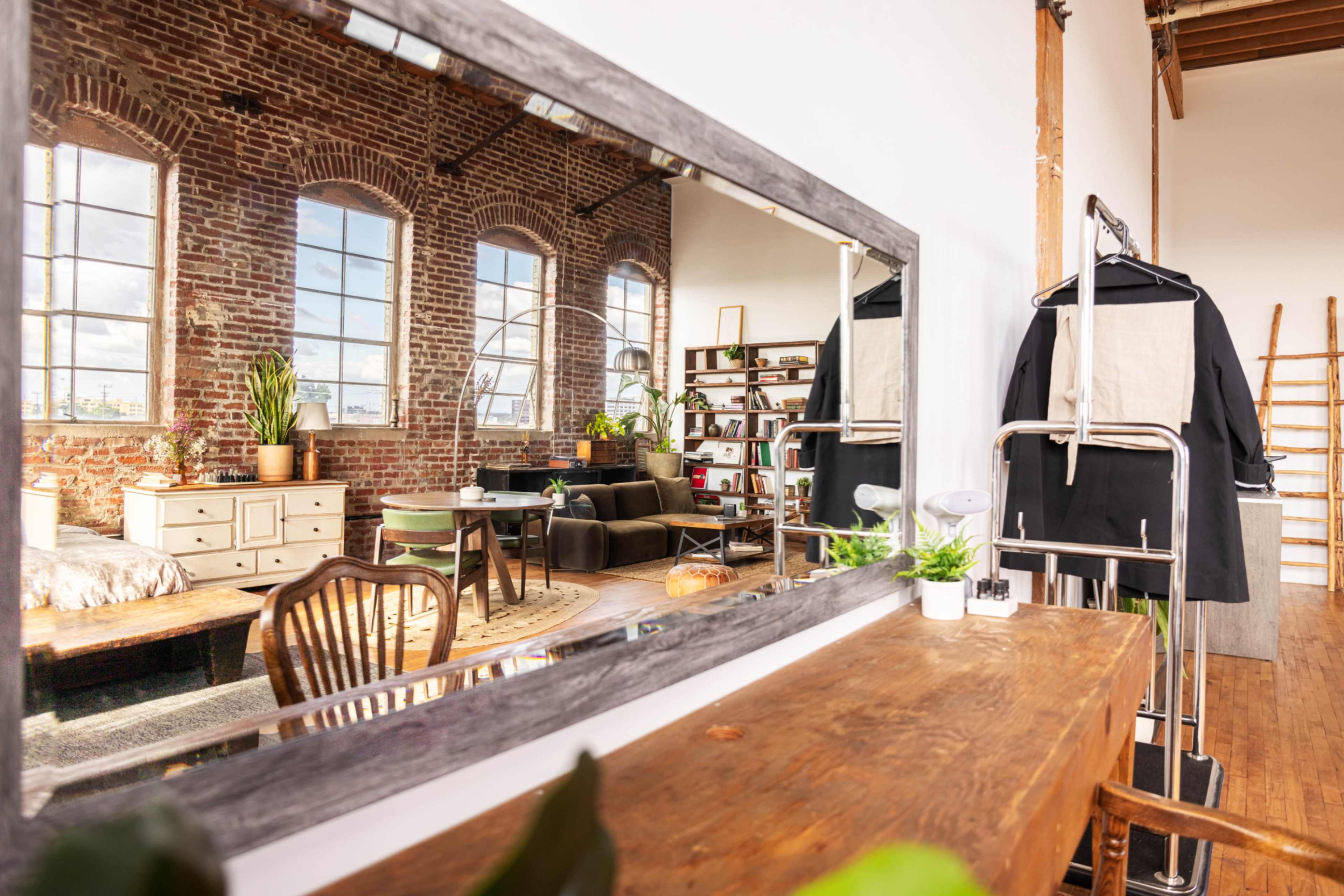A stylish loft with exposed brick walls, a large mirror, and a cozy seating area.