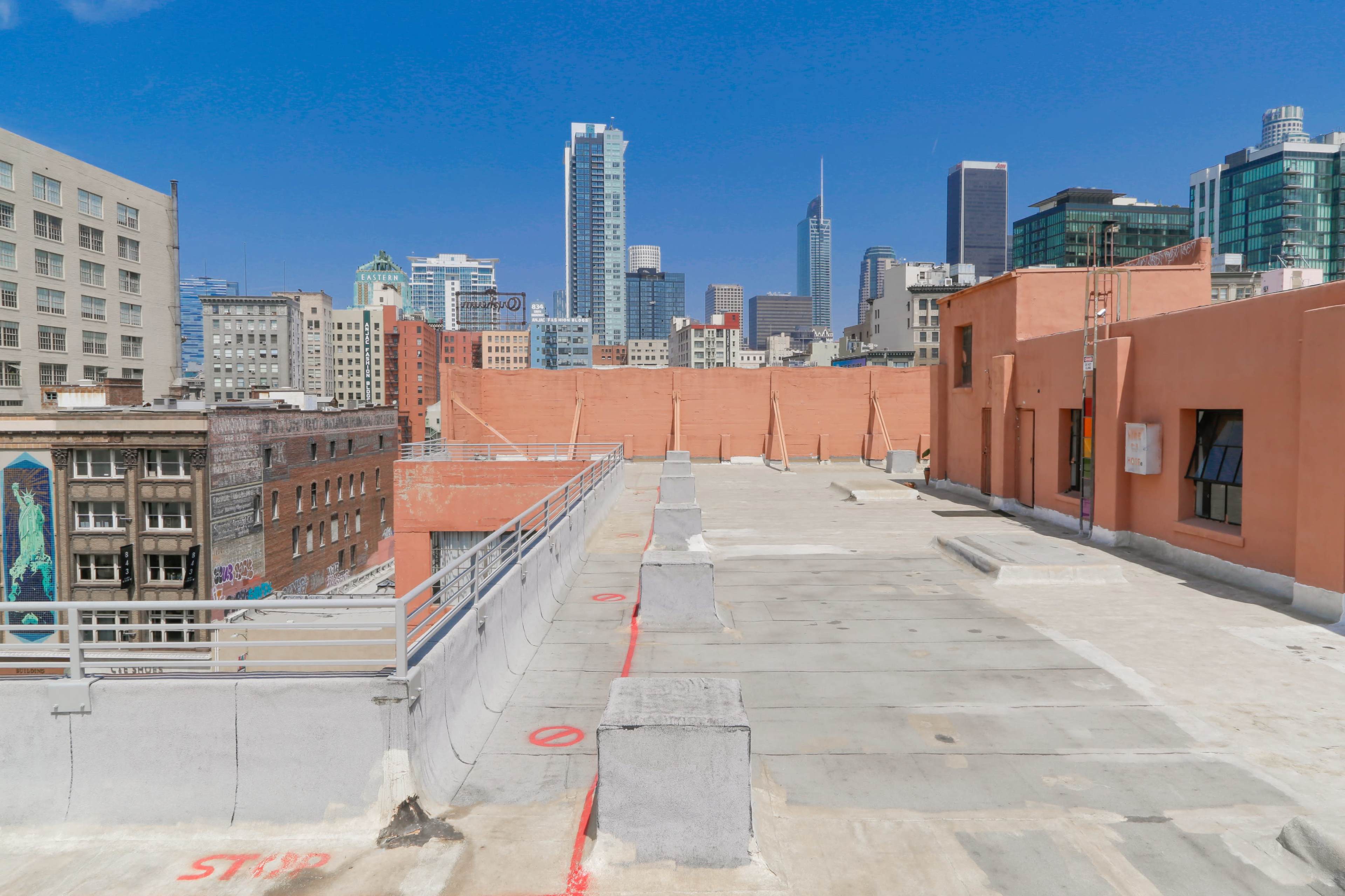 A rooftop view overlooking a city skyline with tall buildings and a clear blue sky.