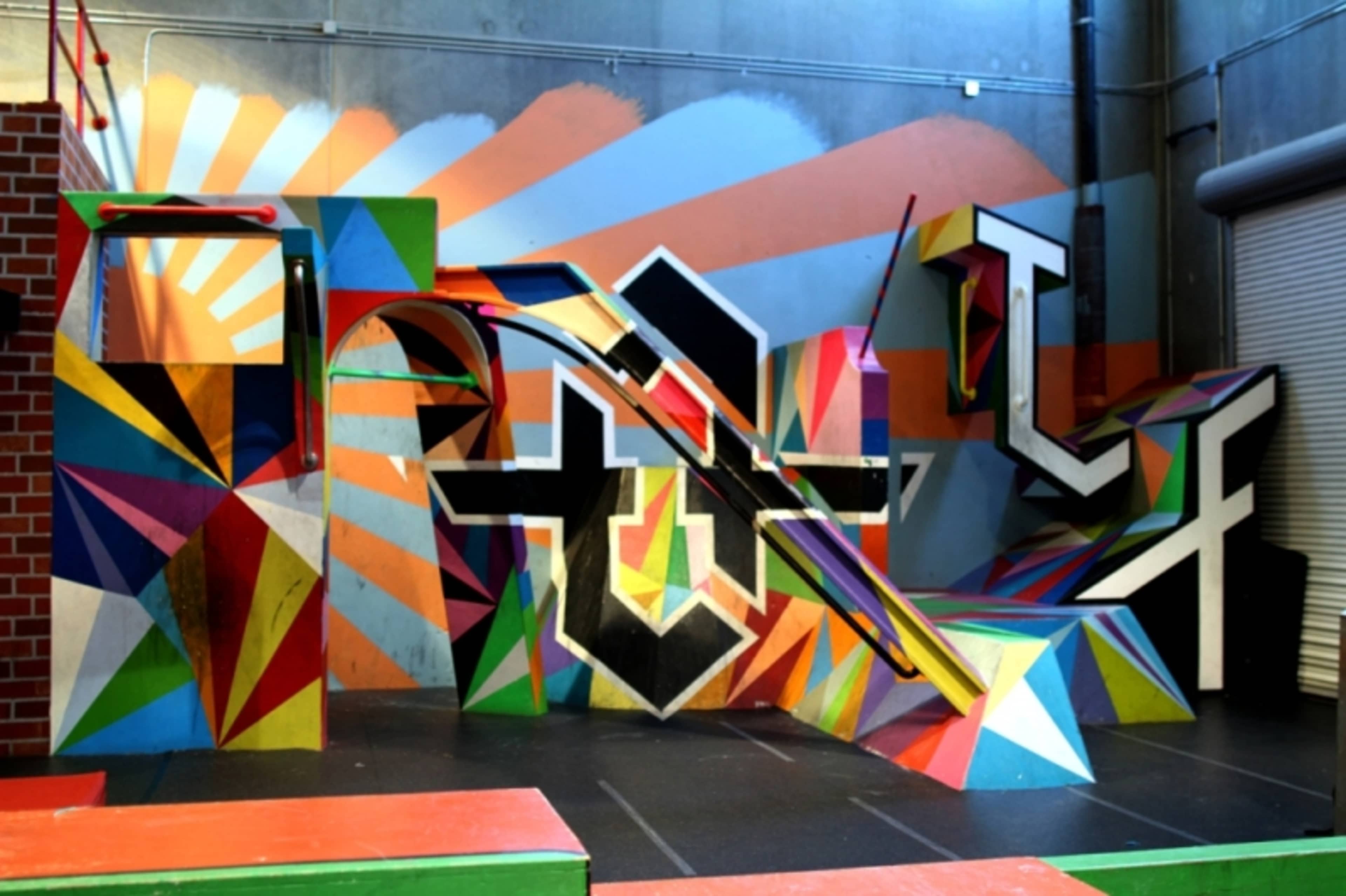 A colorful skatepark with geometric ramps and abstract patterns on the walls.