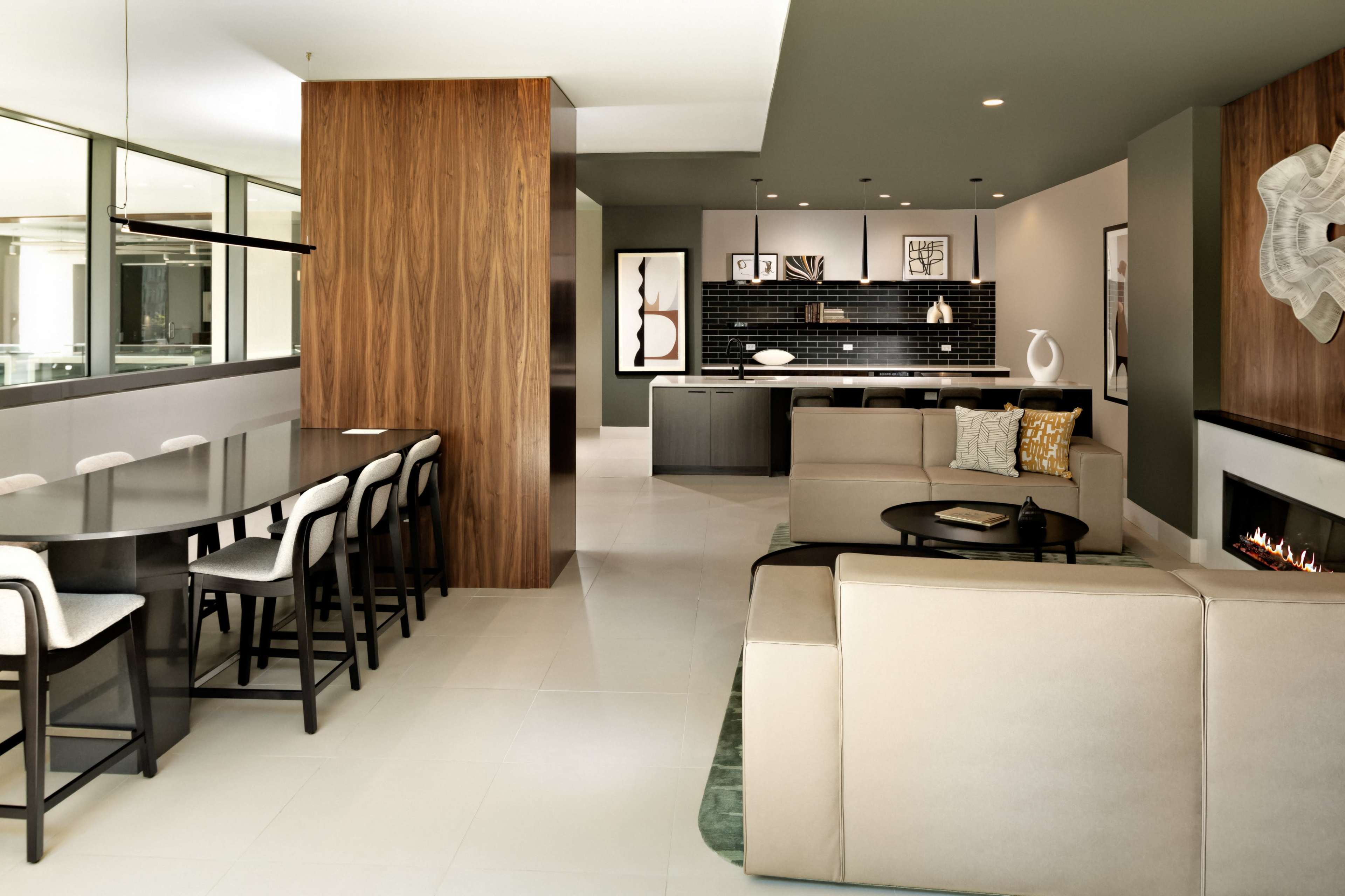 The image shows a modern open-concept living and dining area with a sleek kitchen and minimalistic decor.