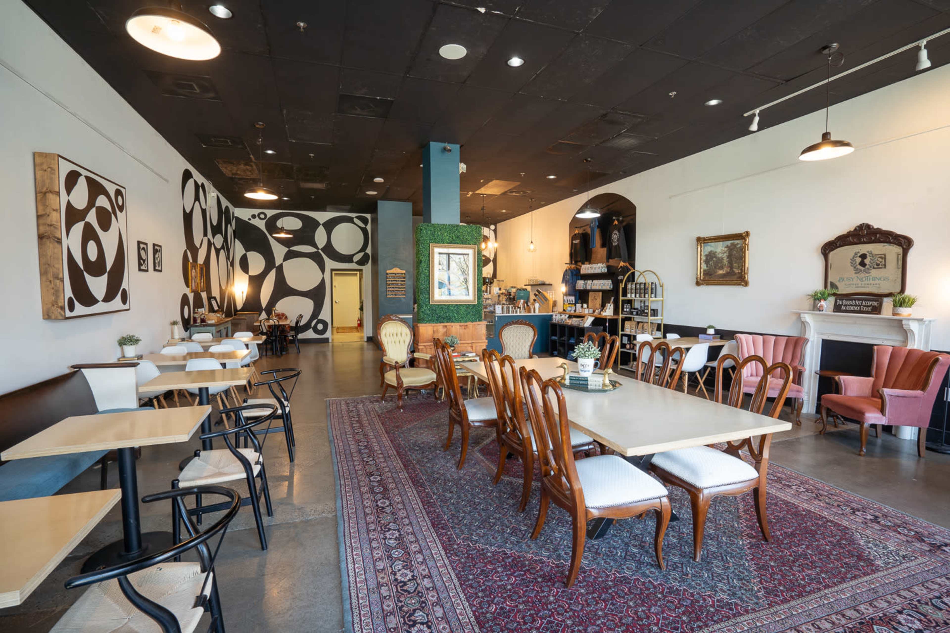 A modern café interior with a mix of table seating and a decorative rug.