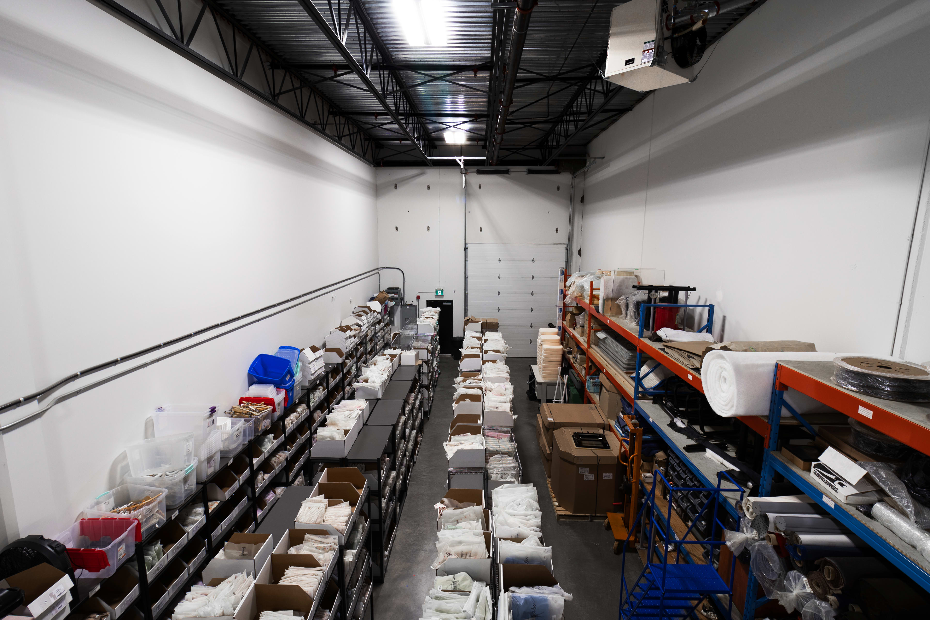 A large storage facility with shelving units stacked with boxes and supplies along the length of the room.