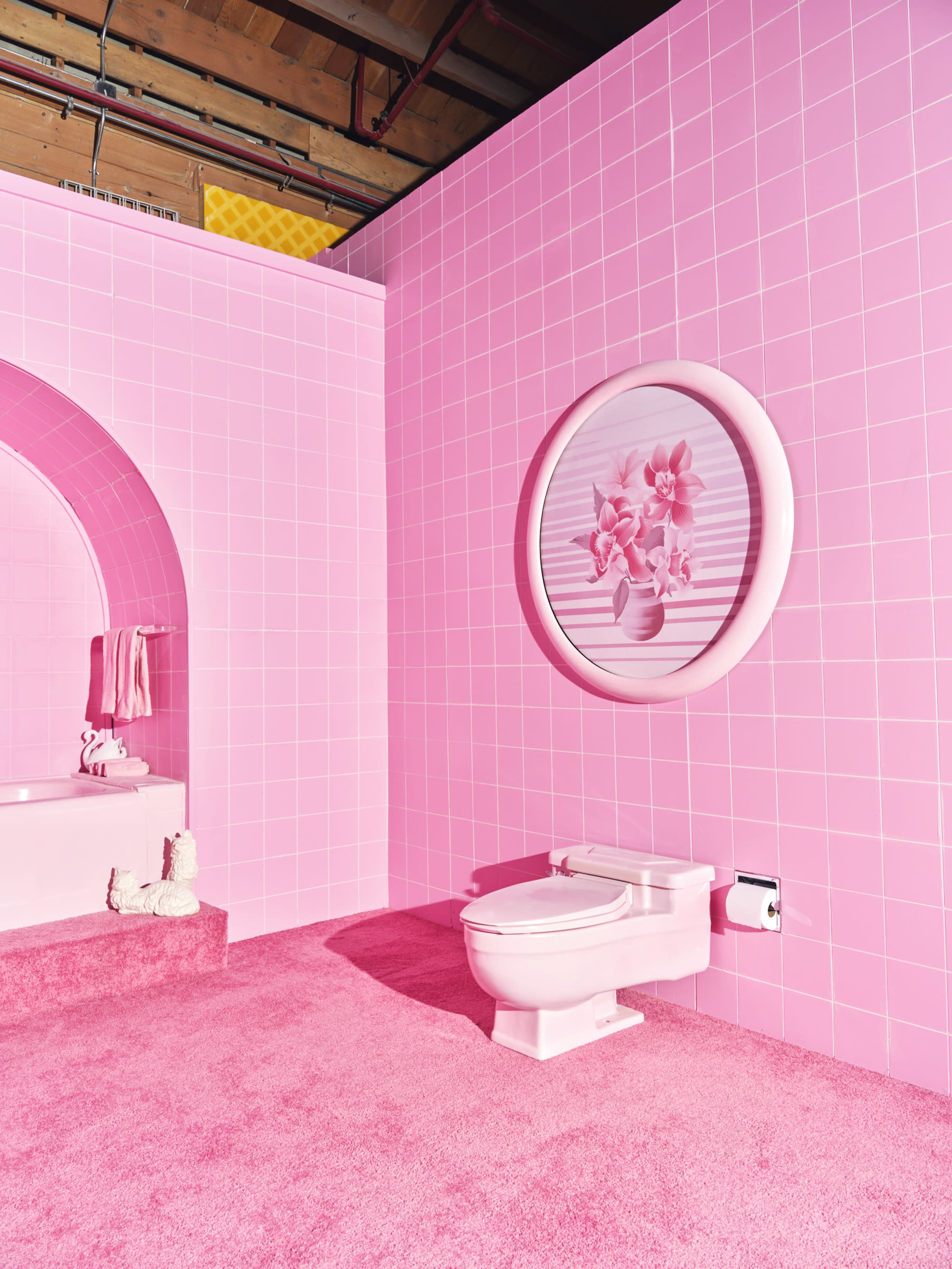 The scene features a bathroom with pink tiled walls, a pink plush carpet, a white toilet, and a round floral wall decoration.