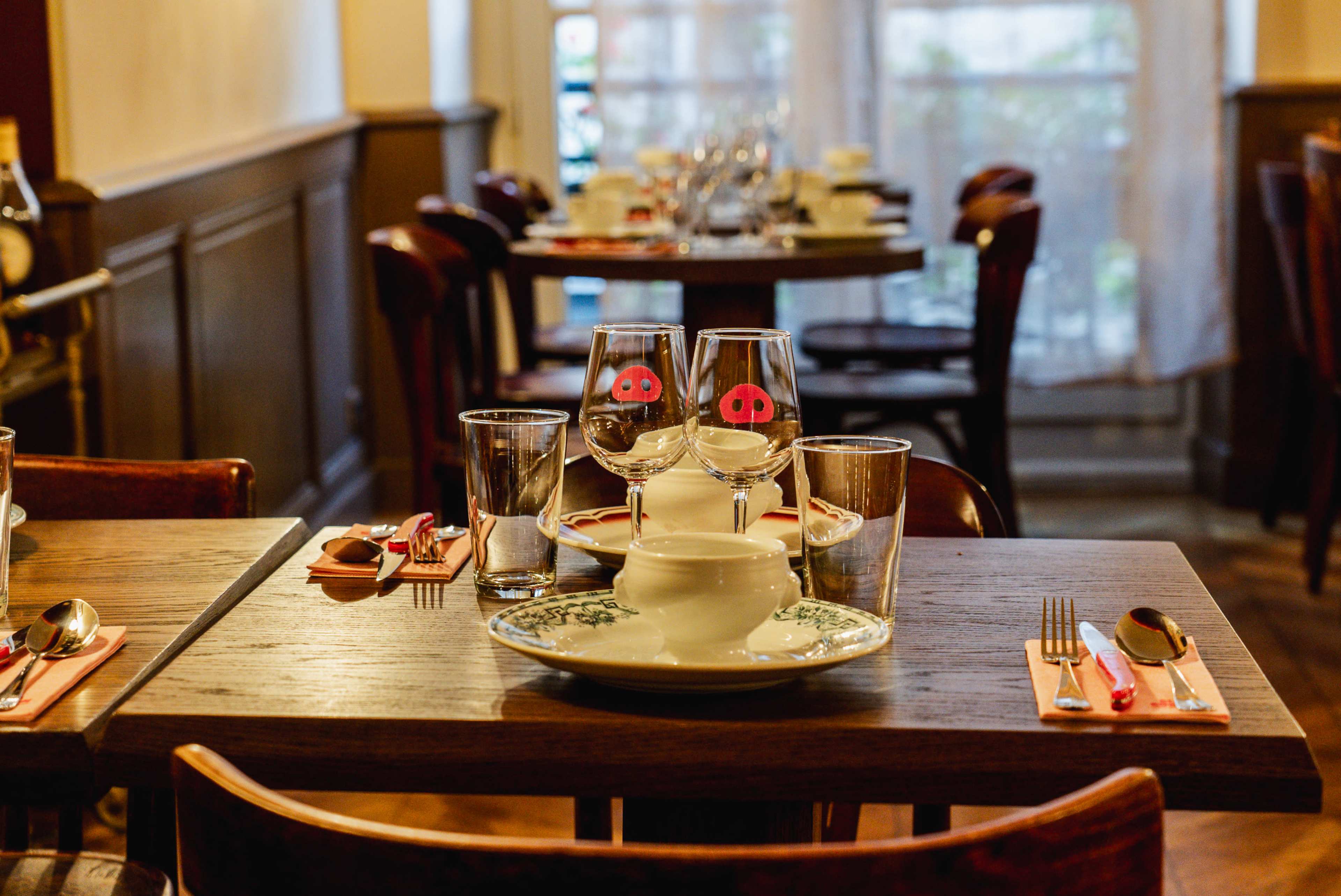 A dining table is set with plates, glasses, utensils, and napkins in a restaurant.