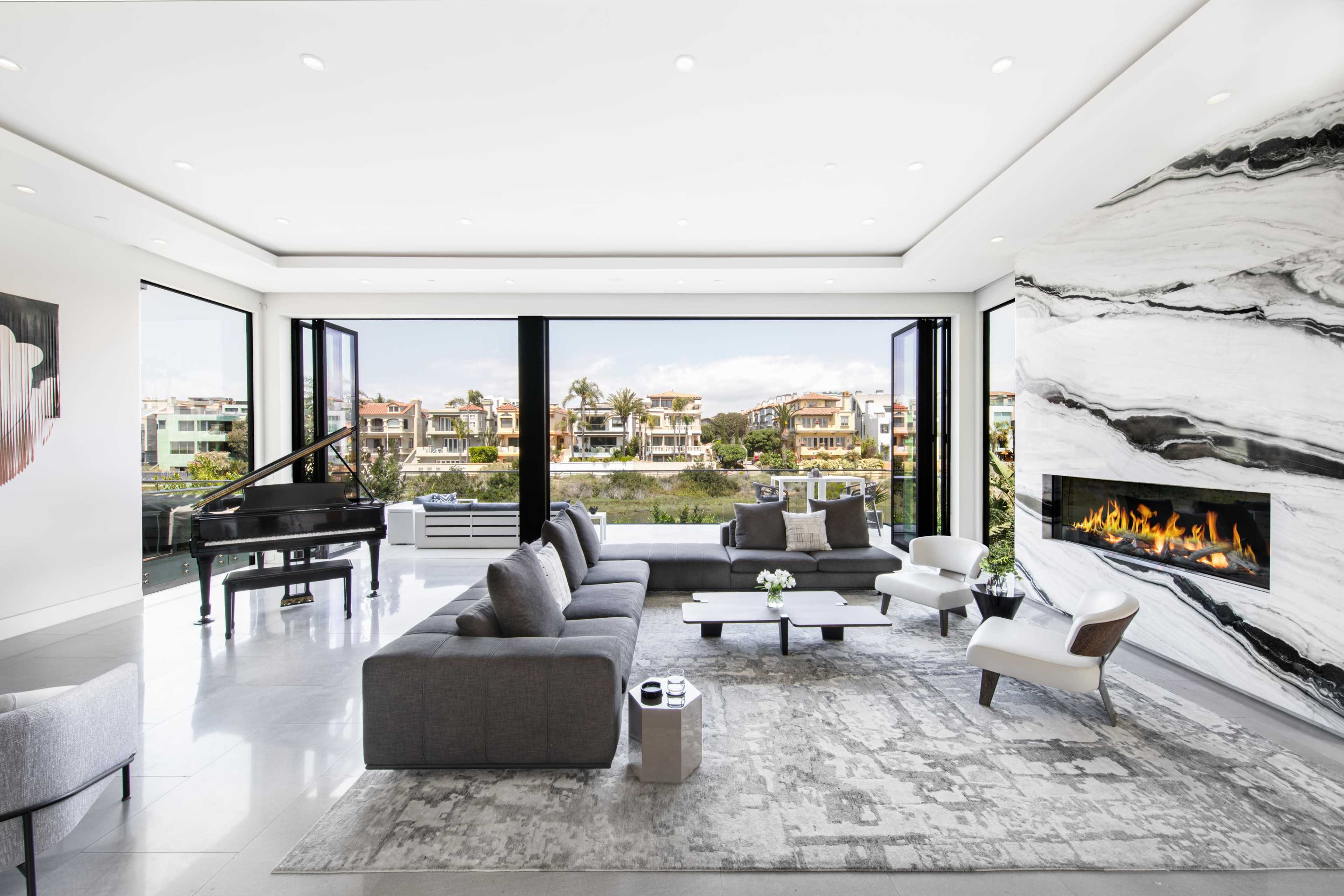A modern living room features a grand piano, sleek furniture, and large windows overlooking a waterfront view.