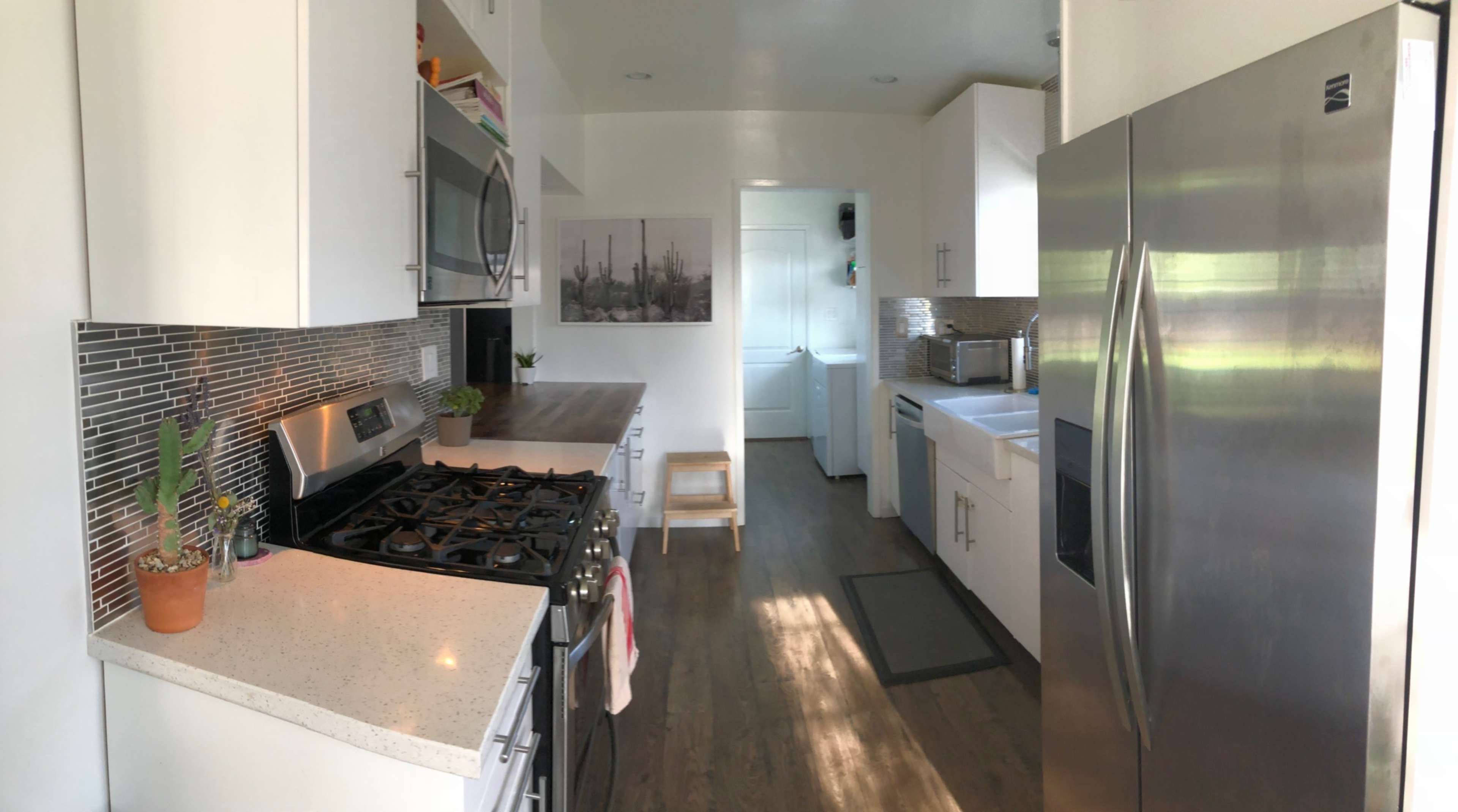 A bright kitchen features modern appliances, white cabinets, and a large window that illuminates the space.