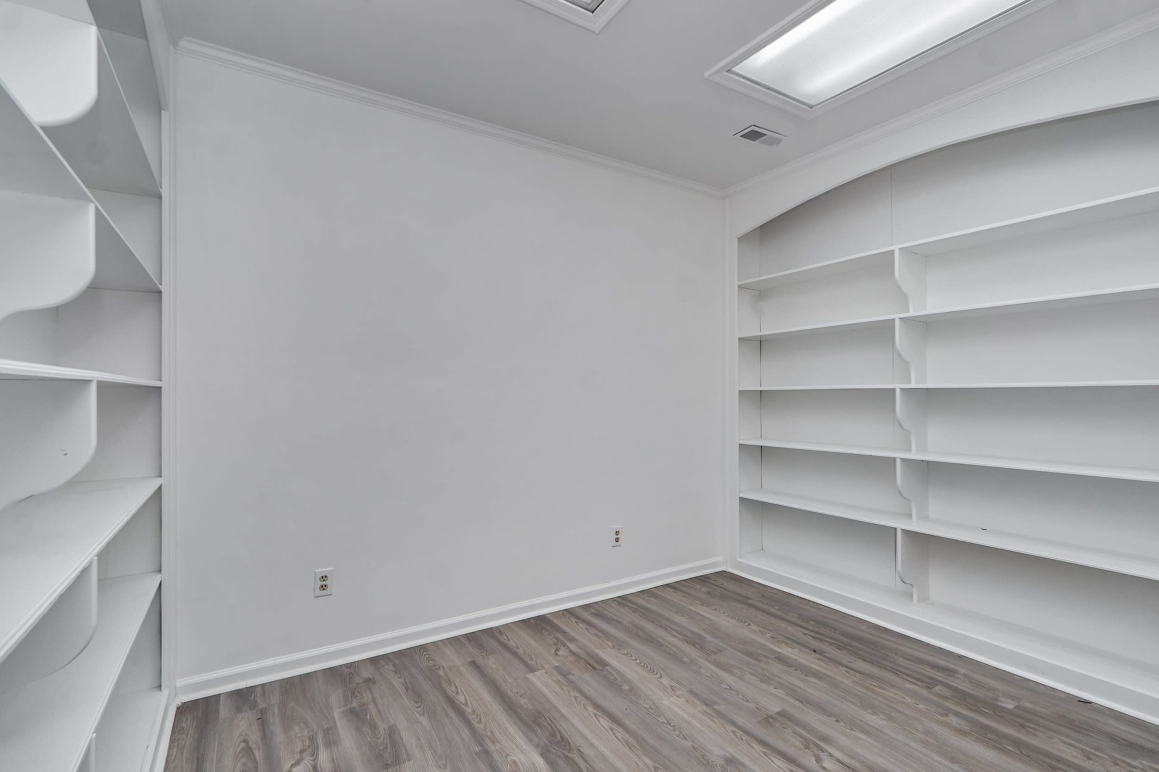 Aempty room with white walls and built-in white shelves on either side.