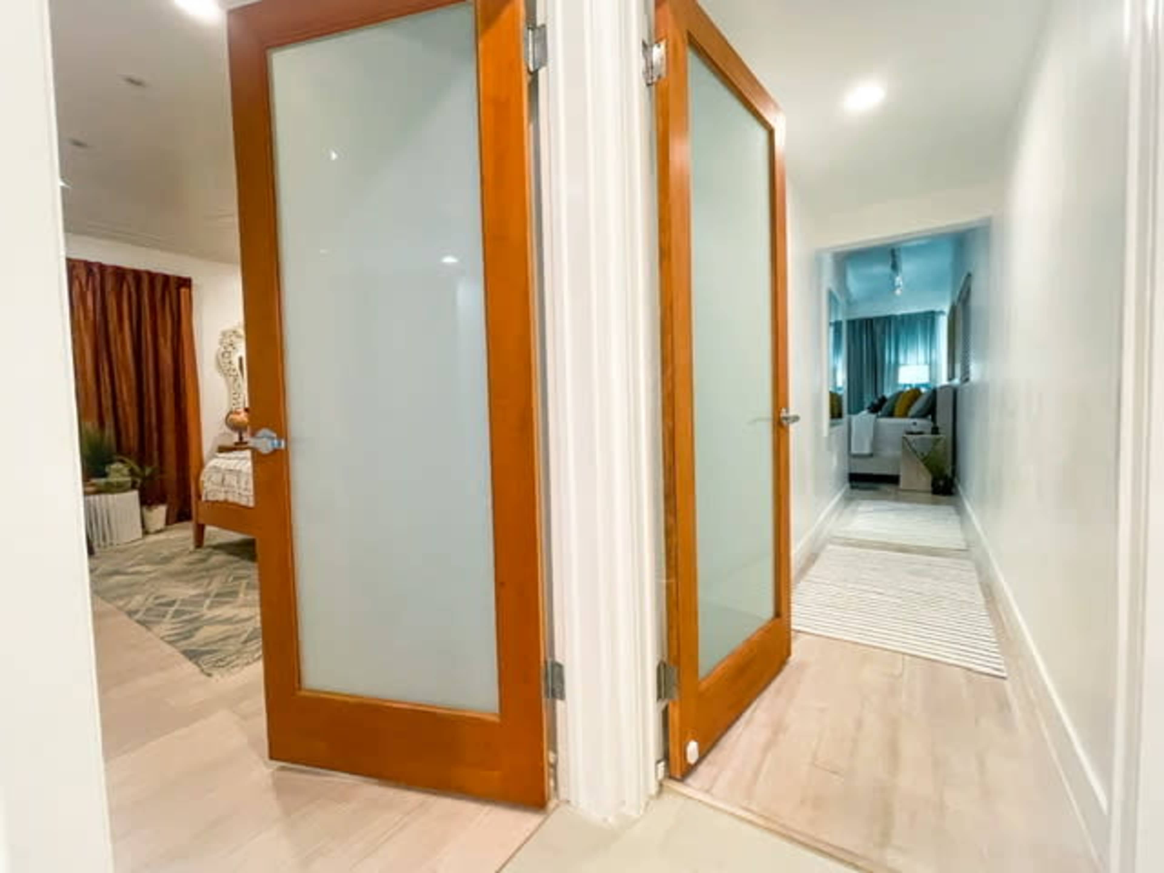 A hallway featuring two wooden doors with glass panels, leading to adjacent rooms.