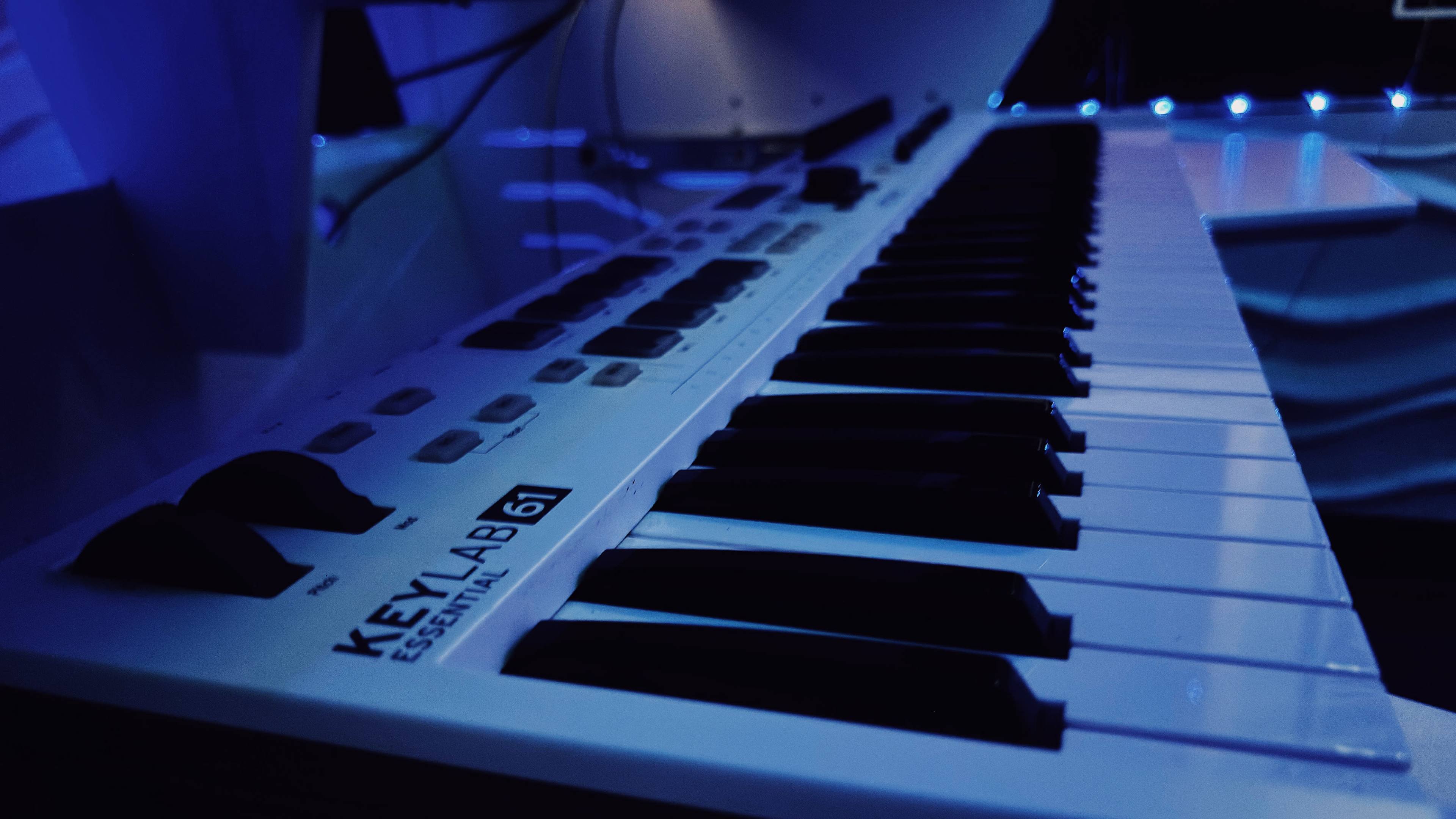 A close-up view of a KeyLab 61 keyboard with black and white keys, illuminated by blue lighting.
