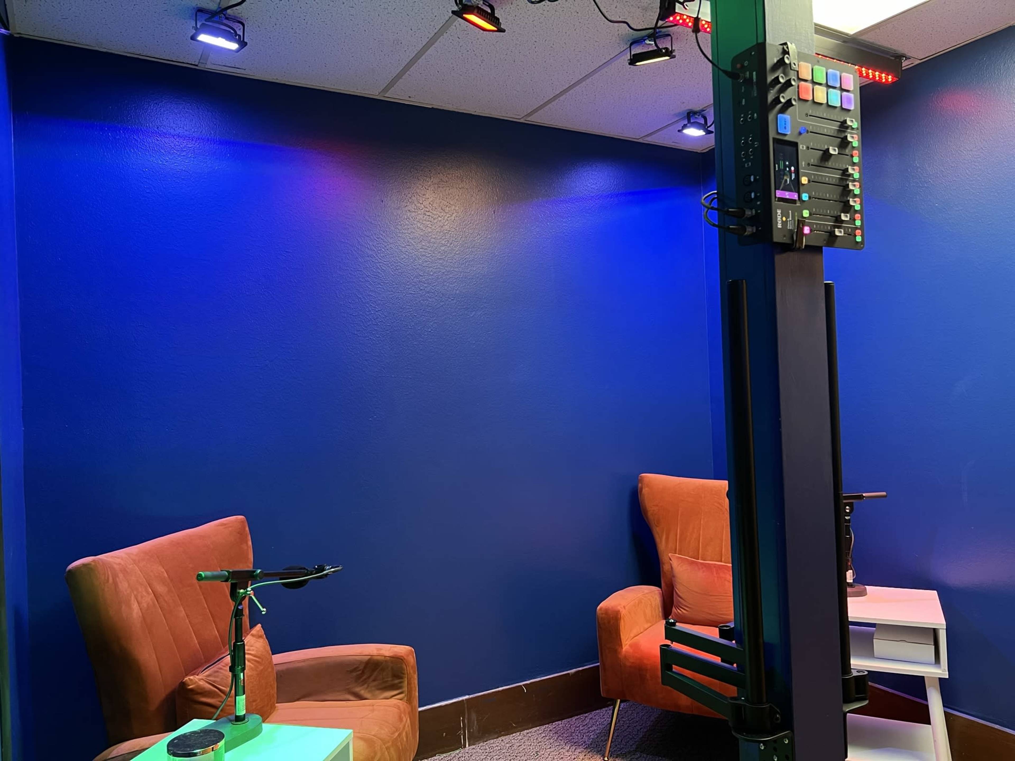 The image shows a small room with blue walls, two brown chairs, and various lighting fixtures on the ceiling.