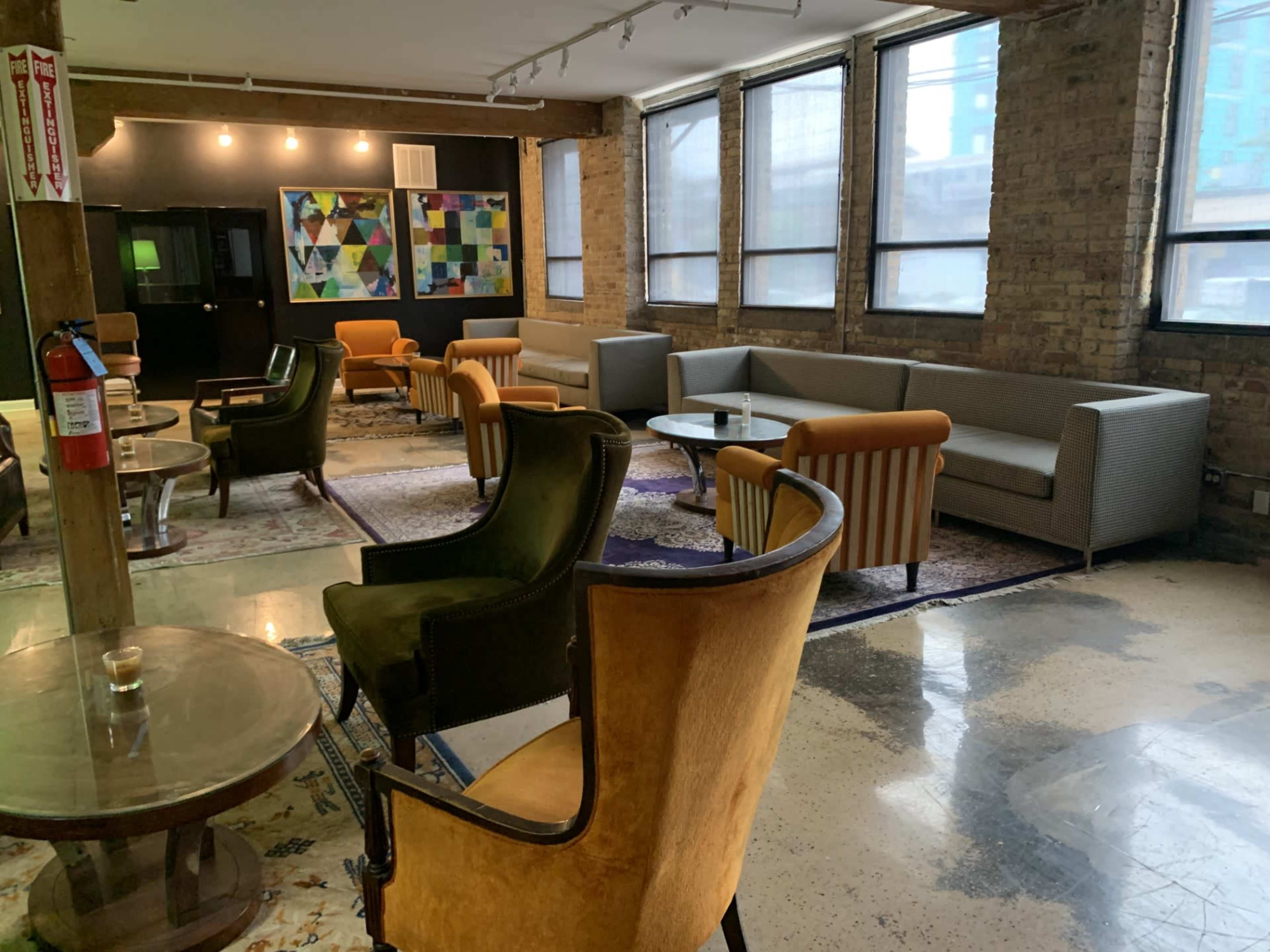 A spacious lounge area with various seating options, including armchairs and sofas, arranged around coffee tables on a patterned rug.