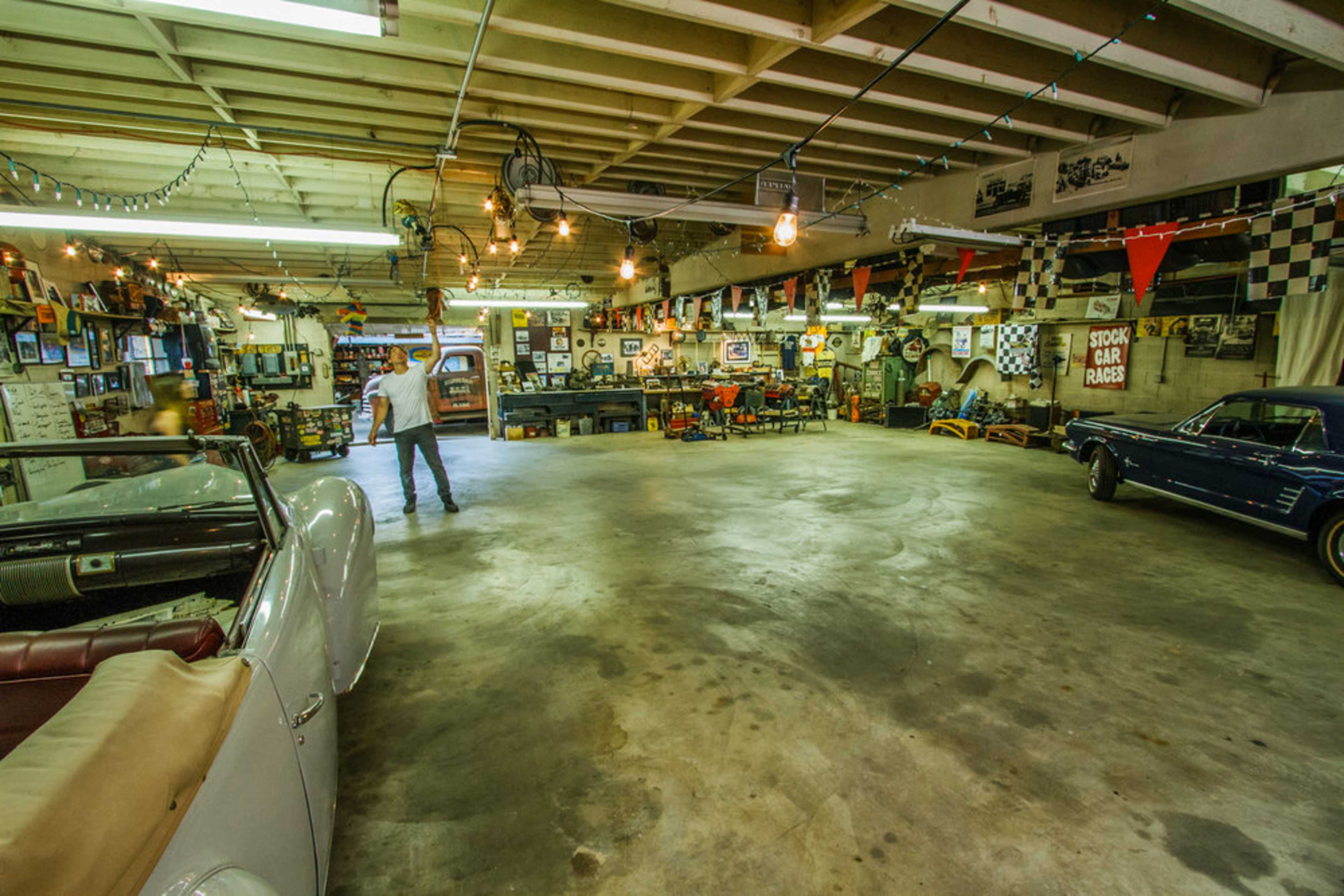 A spacious garage filled with classic cars, memorabilia, and a well-lit interior showcasing various automotive decorations.