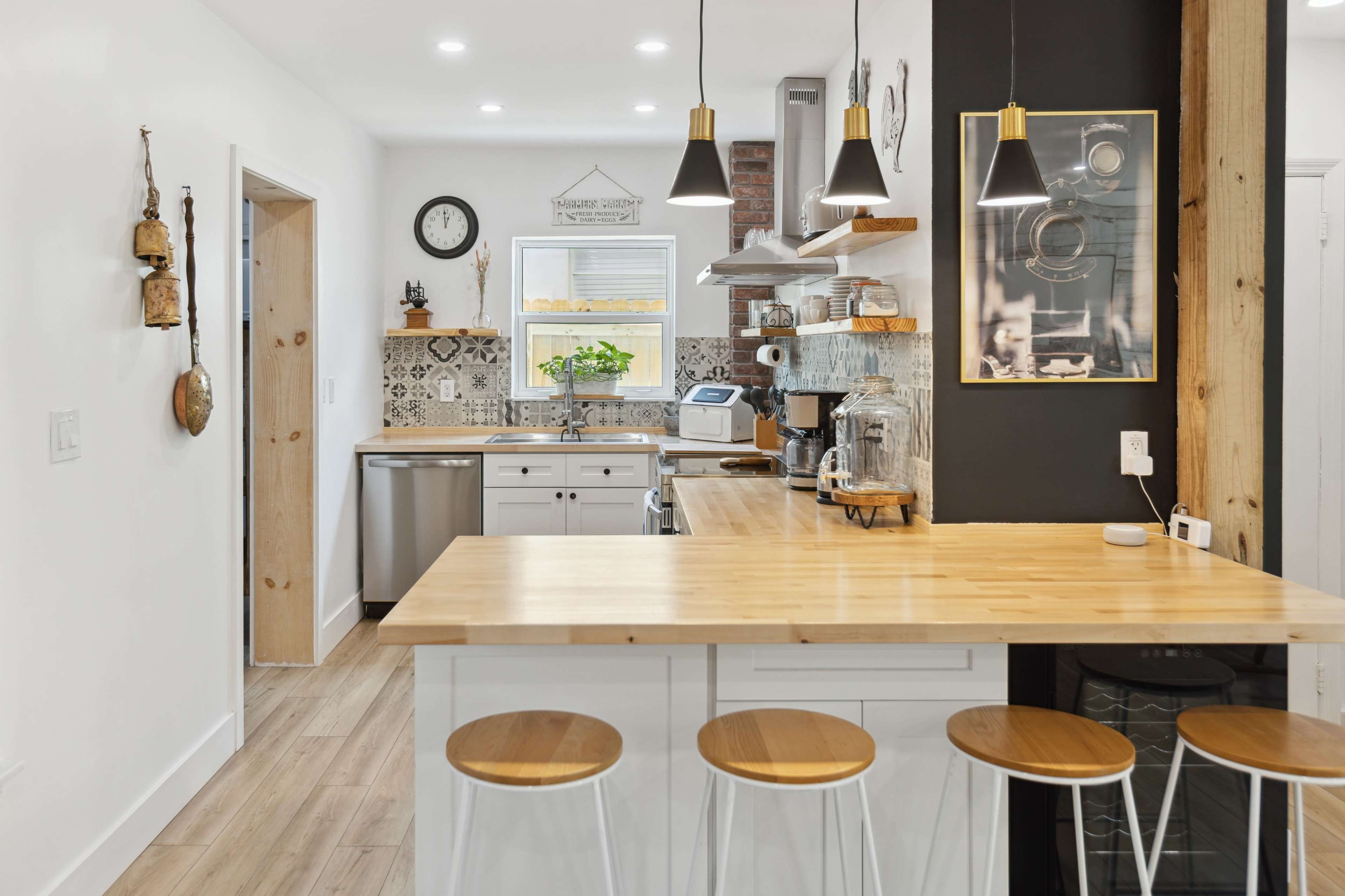 A modern kitchen with a wooden countertop, stainless steel appliances, and an open layout, featuring barstools along one side.