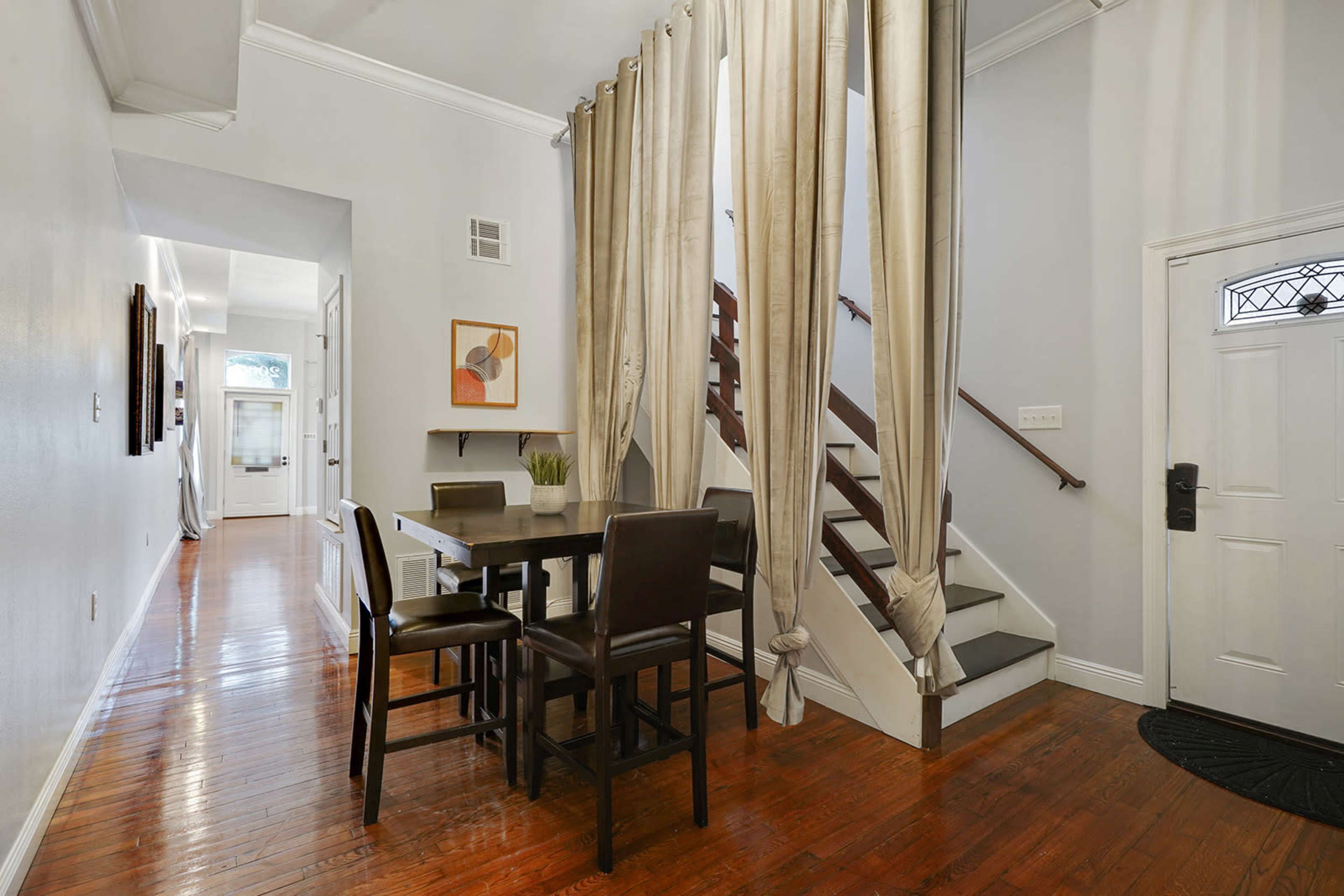 The image shows a hallway with a dining area on the left, a staircase on the right, and an entrance door visible at the front.