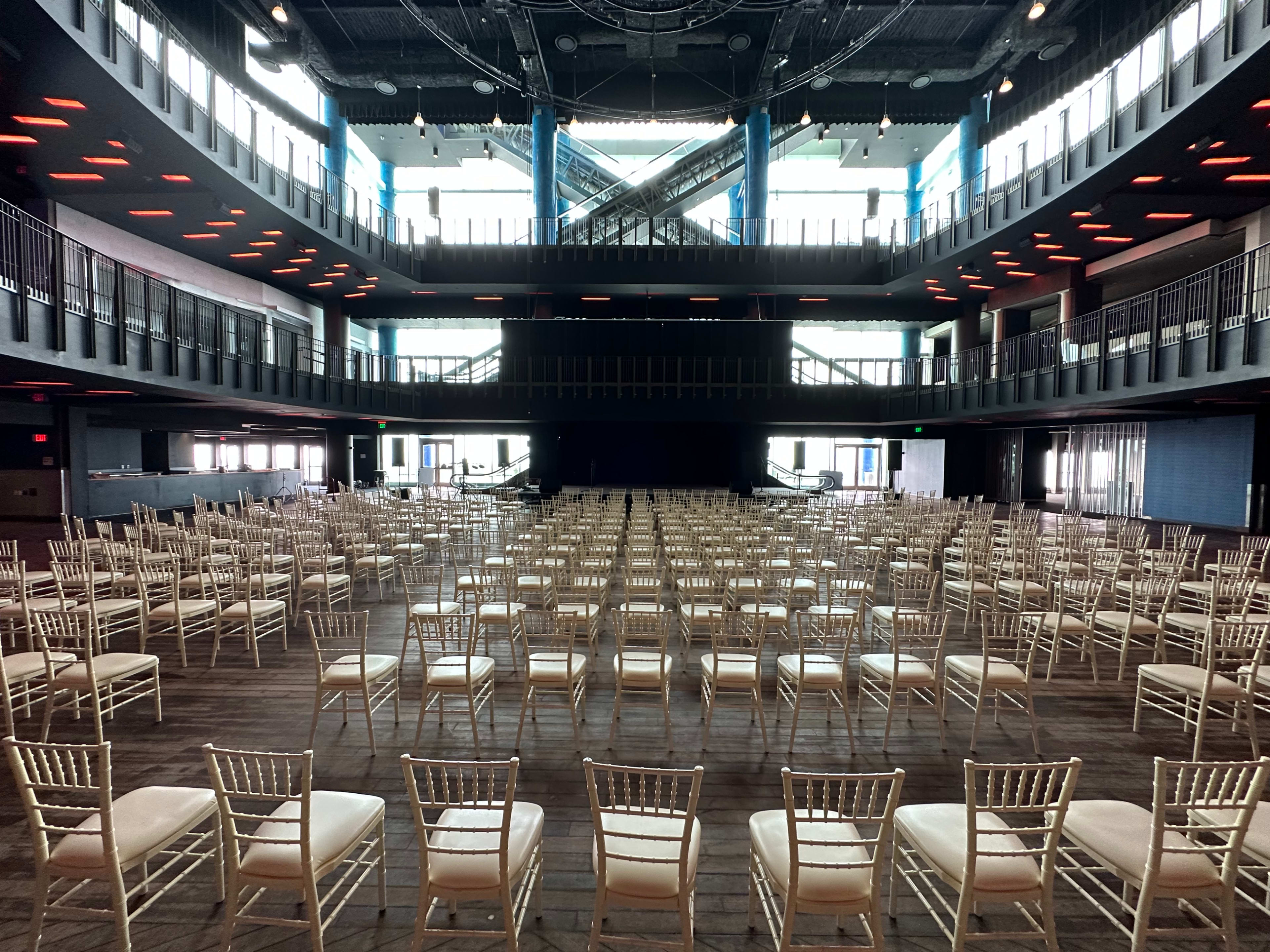 A large indoor venue arranged with numerous empty chairs facing a stage.