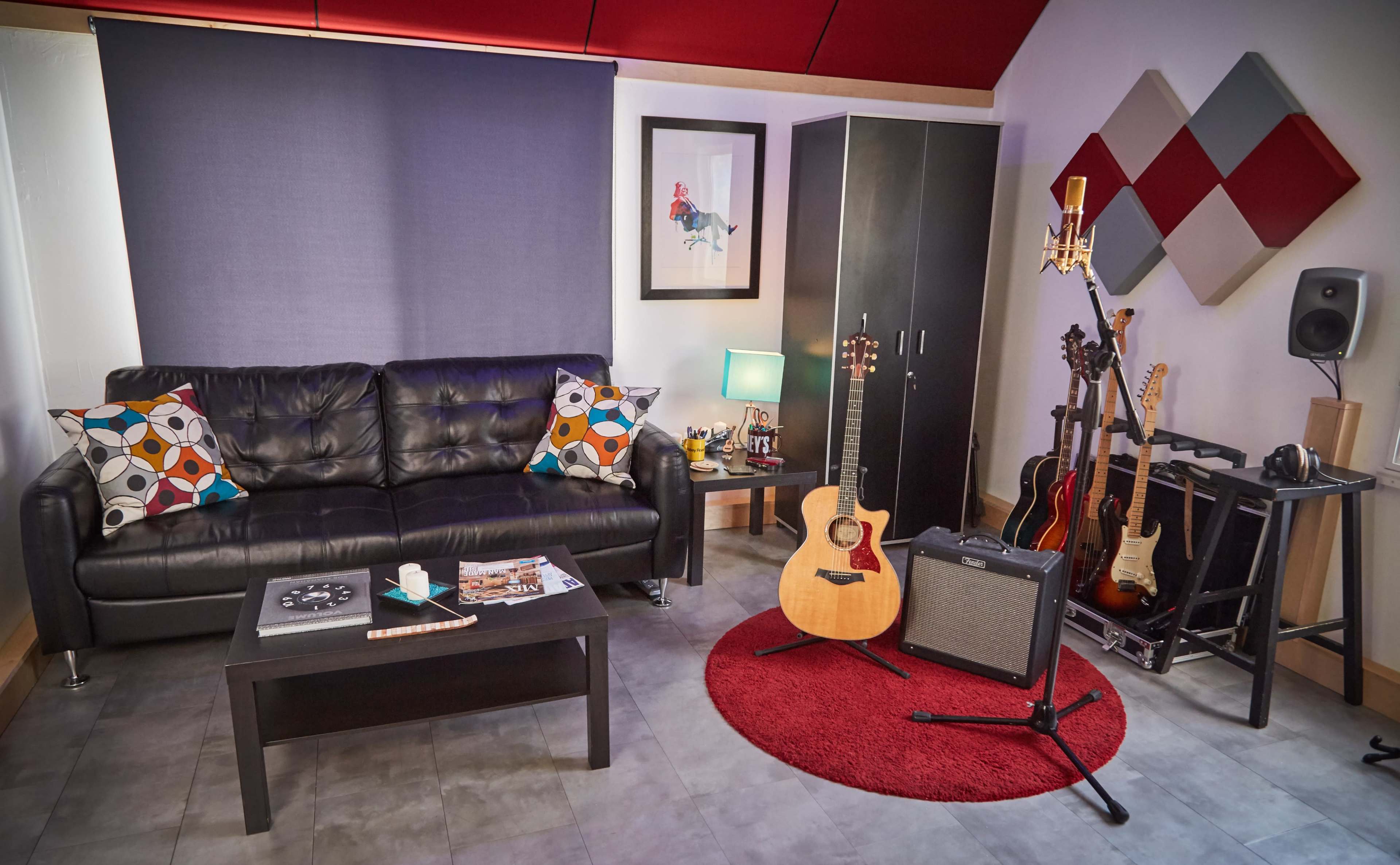 The image depicts a cozy music-themed room featuring a black leather sofa, a coffee table, an acoustic guitar, an amplifier, and several decorative items, set against a backdrop of red and gray accents.