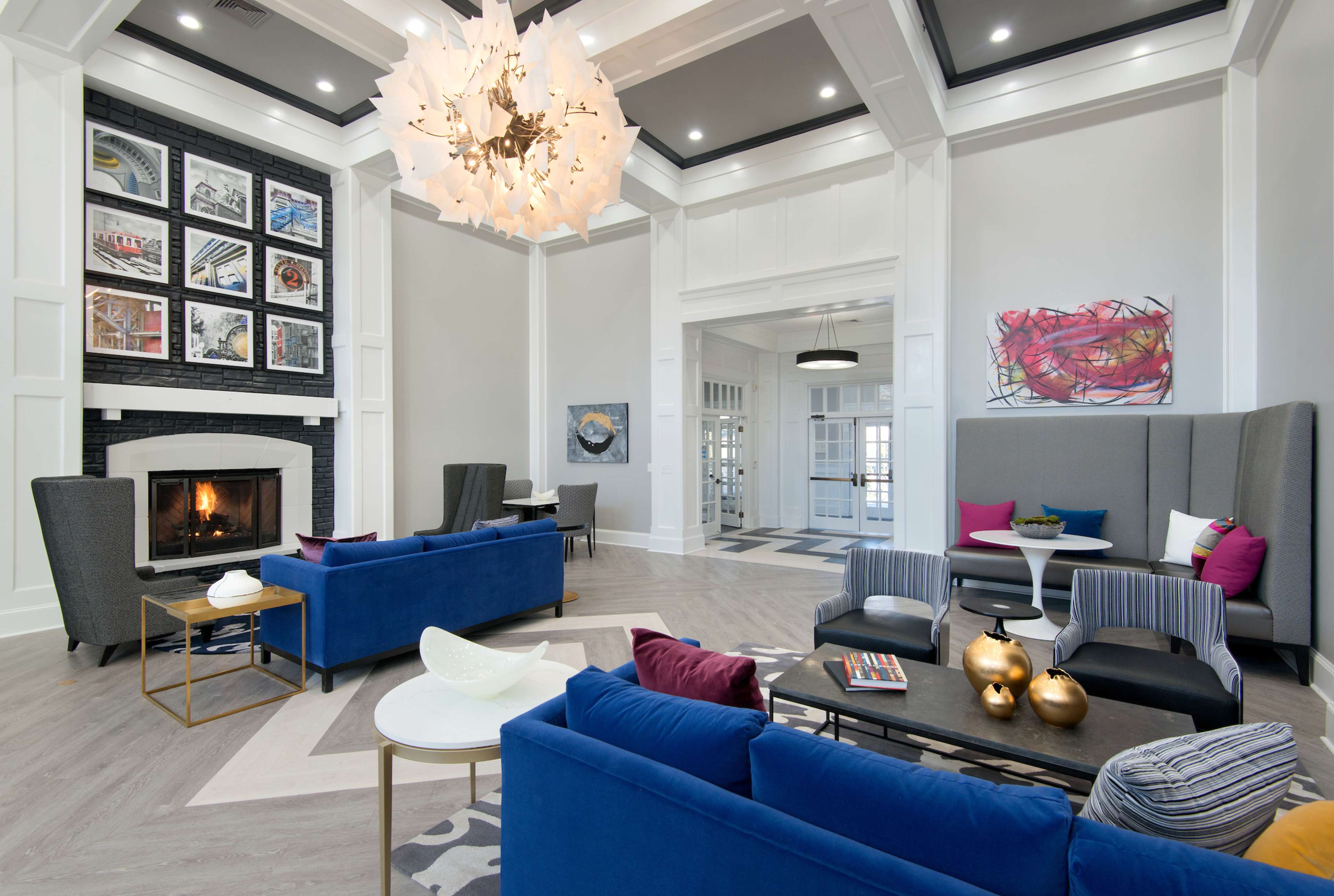 The image depicts a modern living area featuring a fireplace, contemporary seating arrangements, and artwork on the walls.