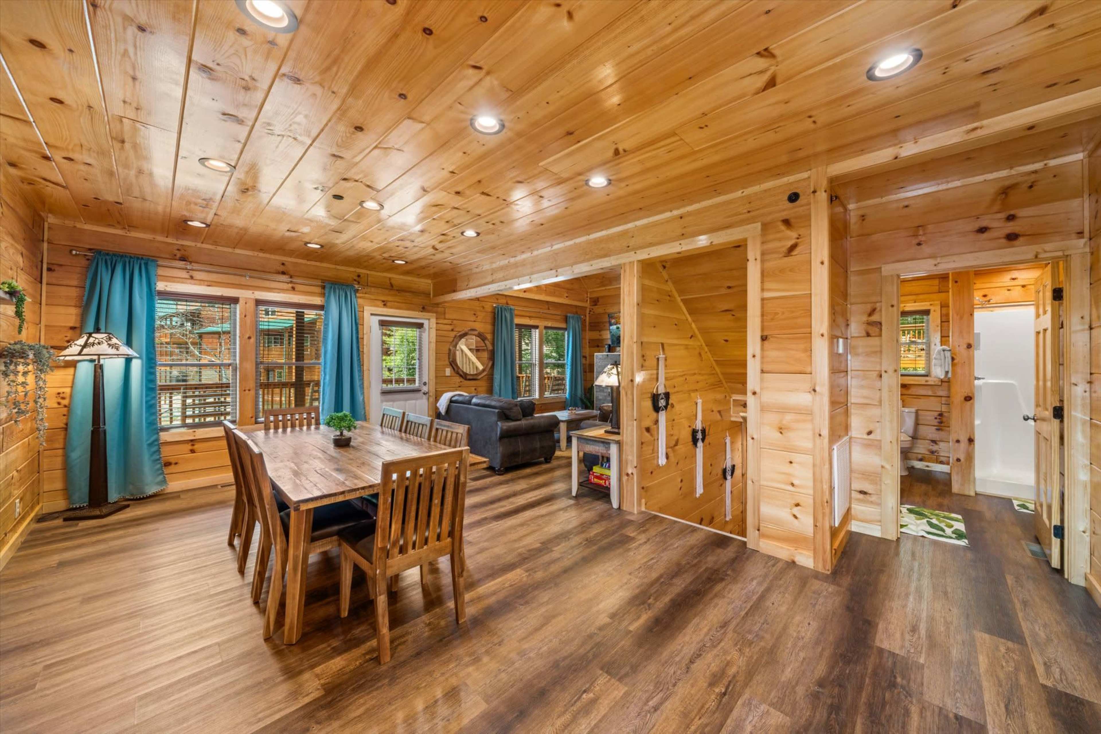 A wood-paneled living space with a dining area, a seating area, and several windows letting in natural light.