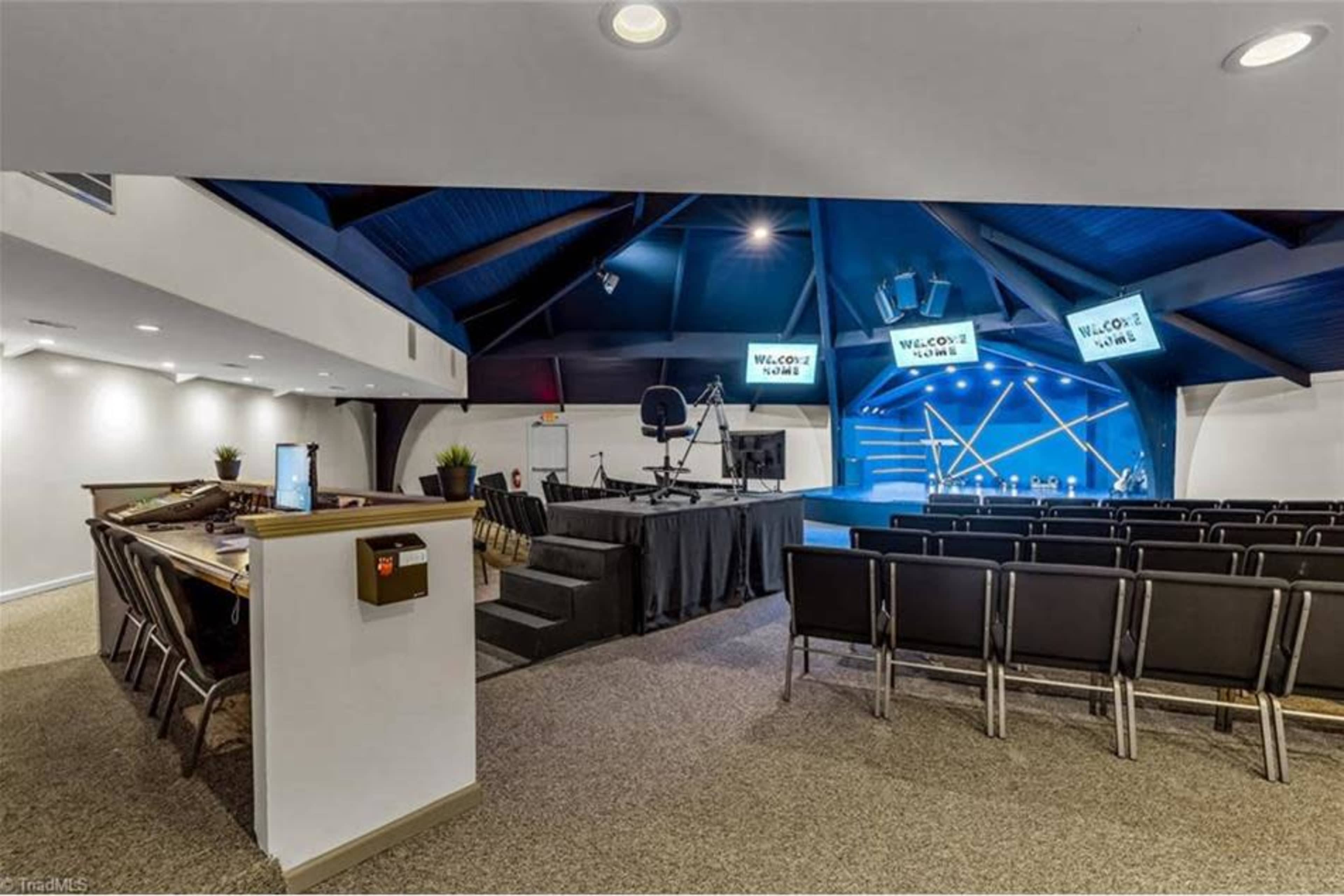 A modern indoor auditorium with a stage, seating area, and technical setup in a well-lit space.