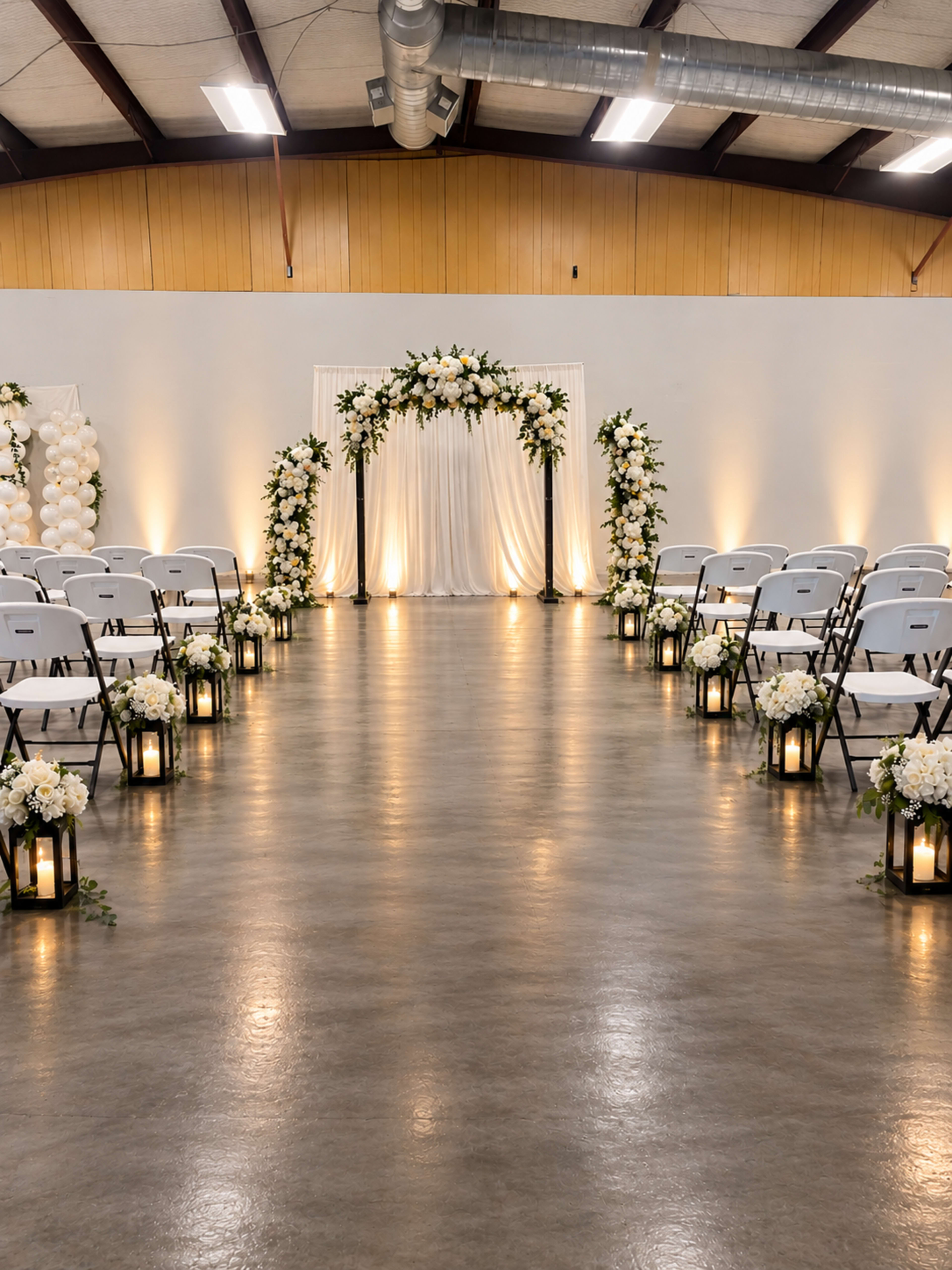 The image shows a decorated indoor event space set up for a ceremony, featuring white chairs arranged in rows facing an altar decorated with flowers and drapery.