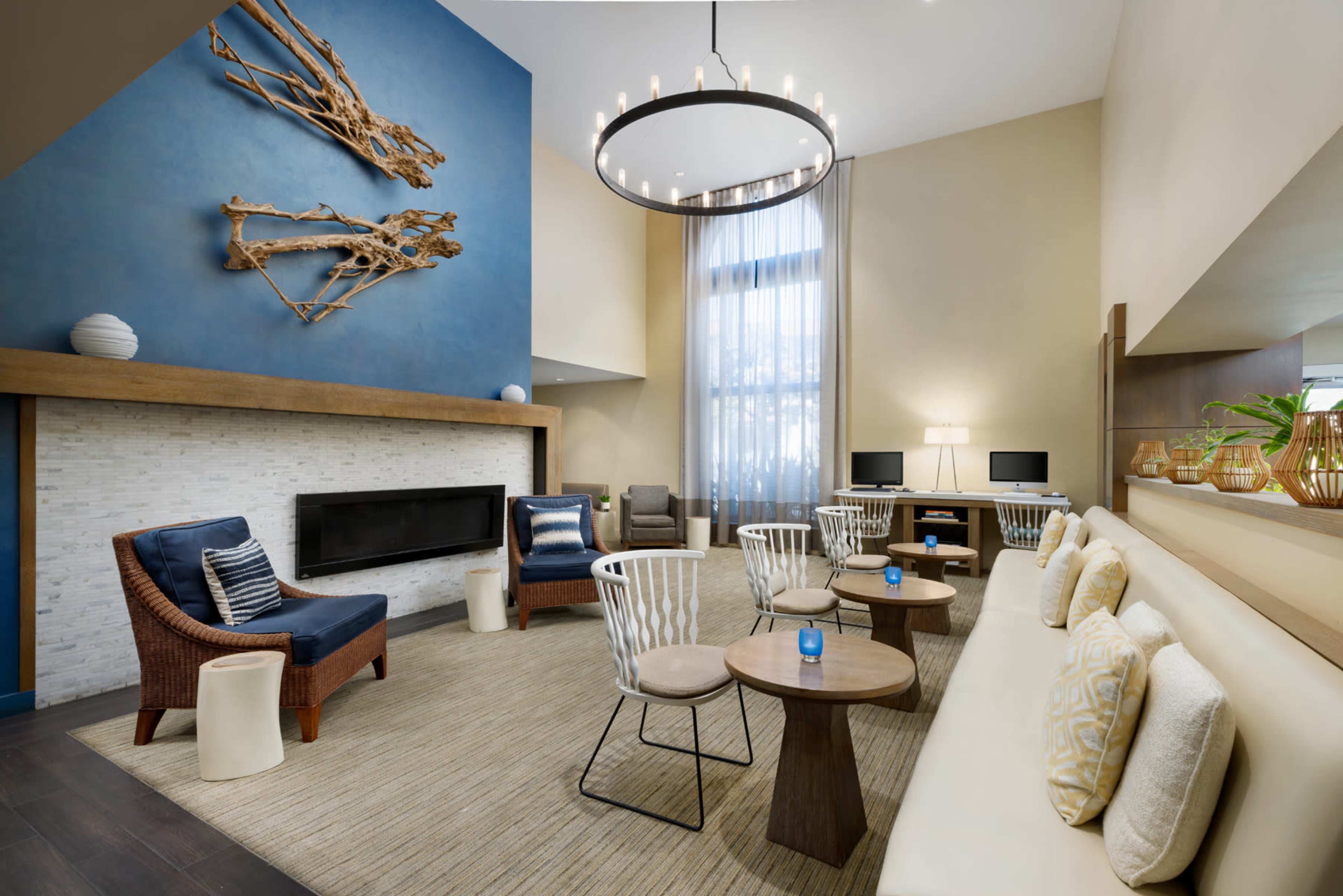 The image shows a modern lounge area featuring a fireplace, comfortable seating, and a large blue wall with decorative artwork.