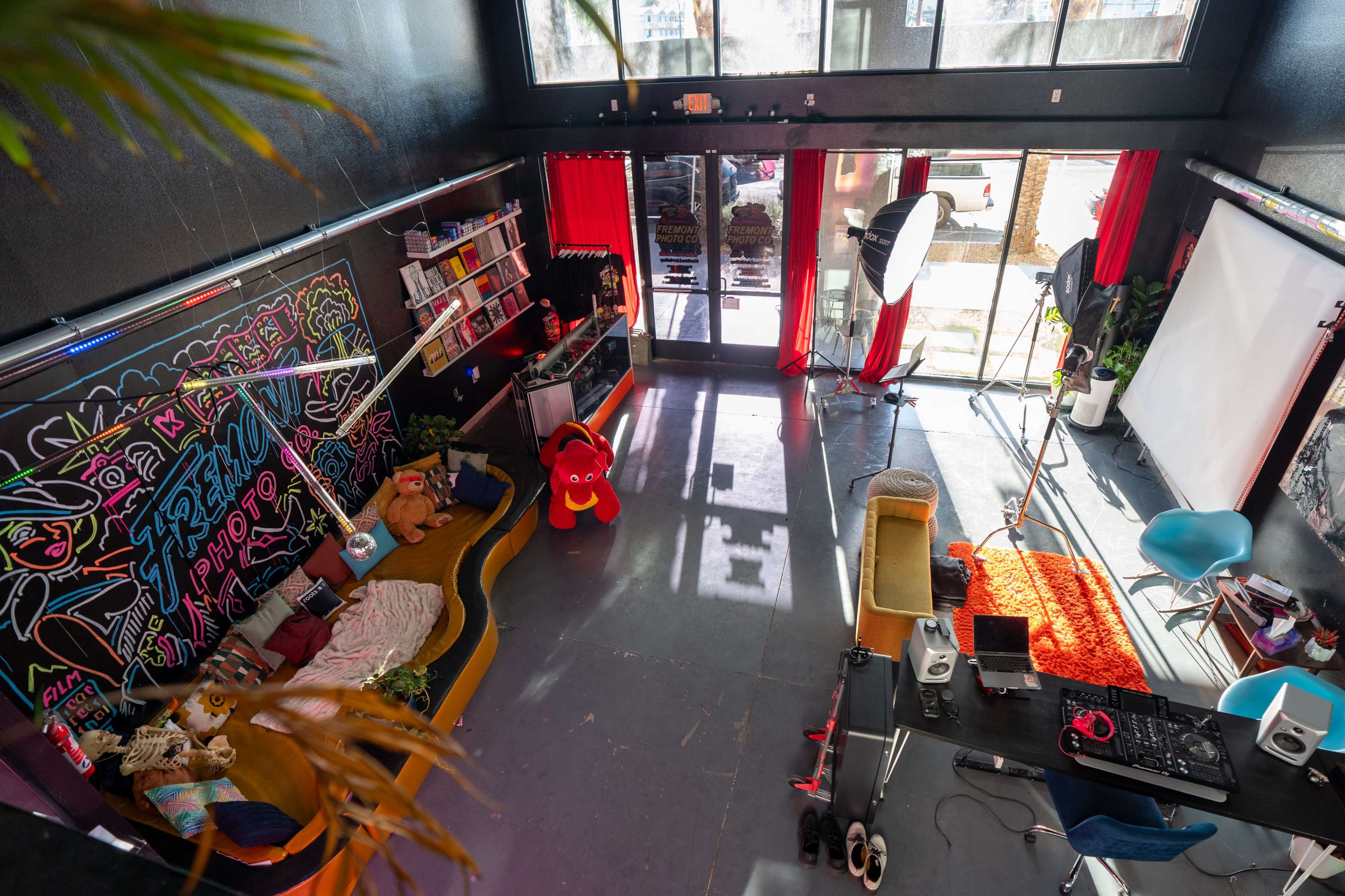 A brightly colored studio space with a large mural, seating areas, and equipment for a photo shoot.