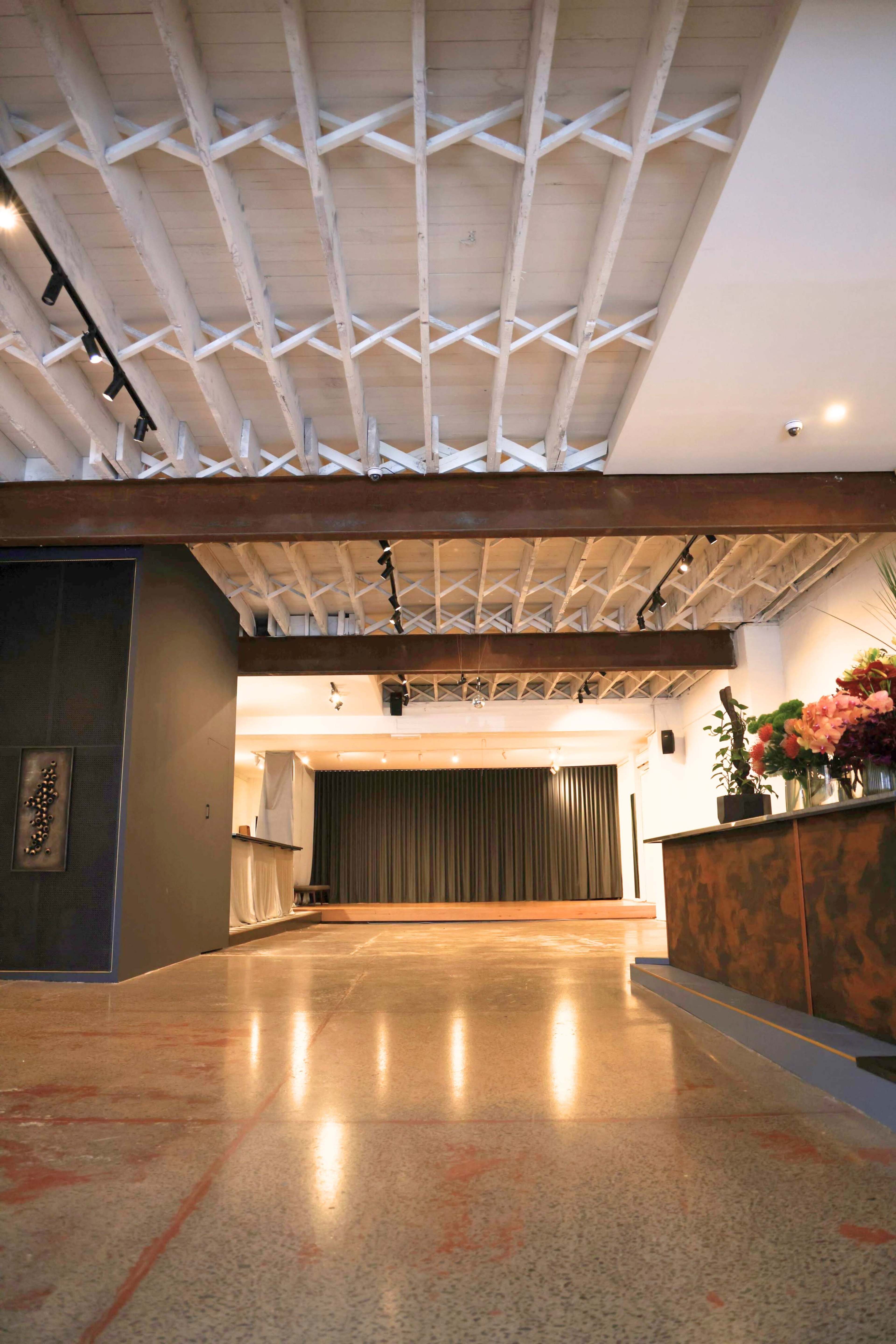 An interior space with exposed beams, polished concrete flooring, and a bar area in the foreground.