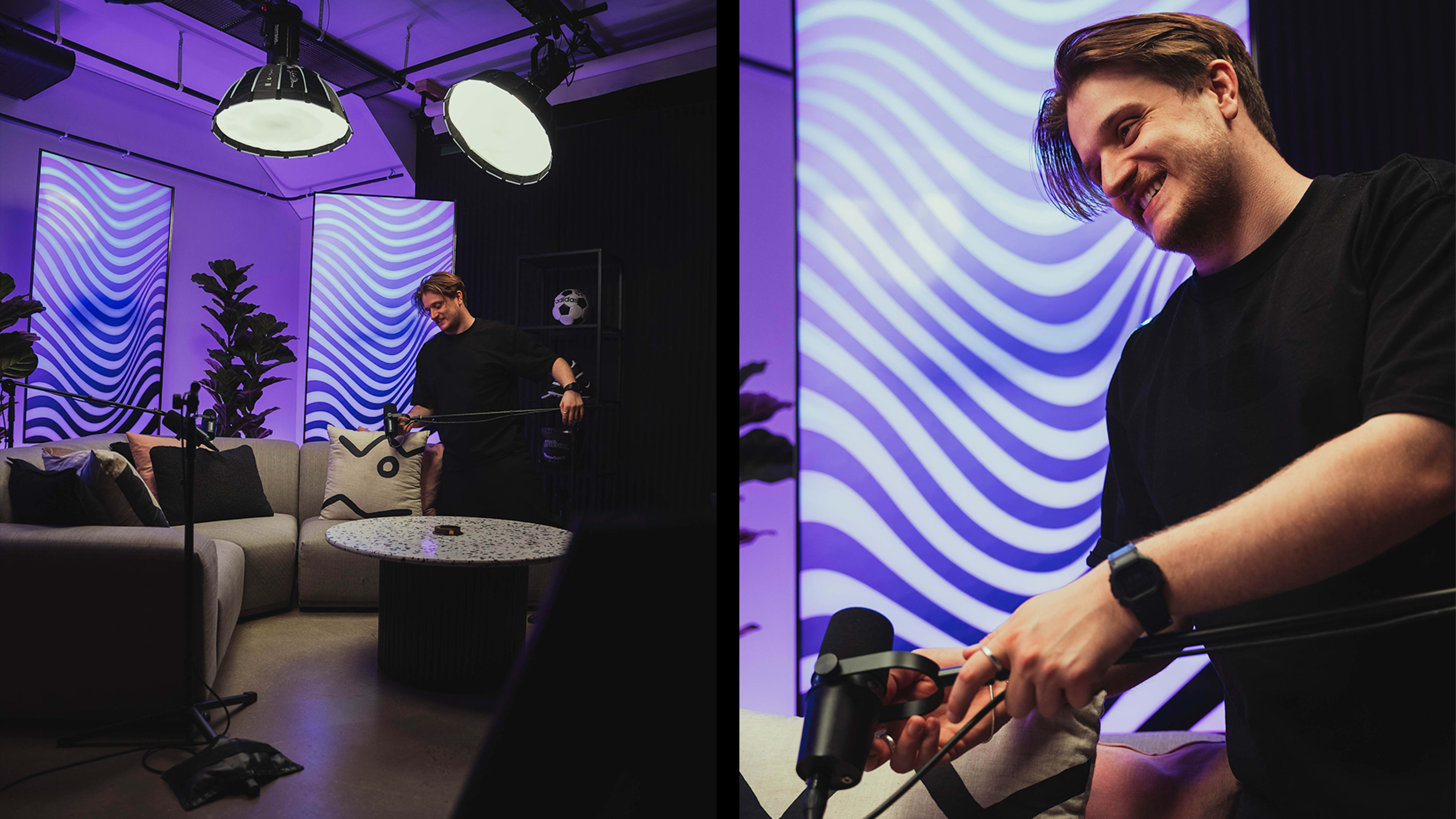 A man is setting up microphones in a modern studio with patterned light displays and a comfortable seating area.